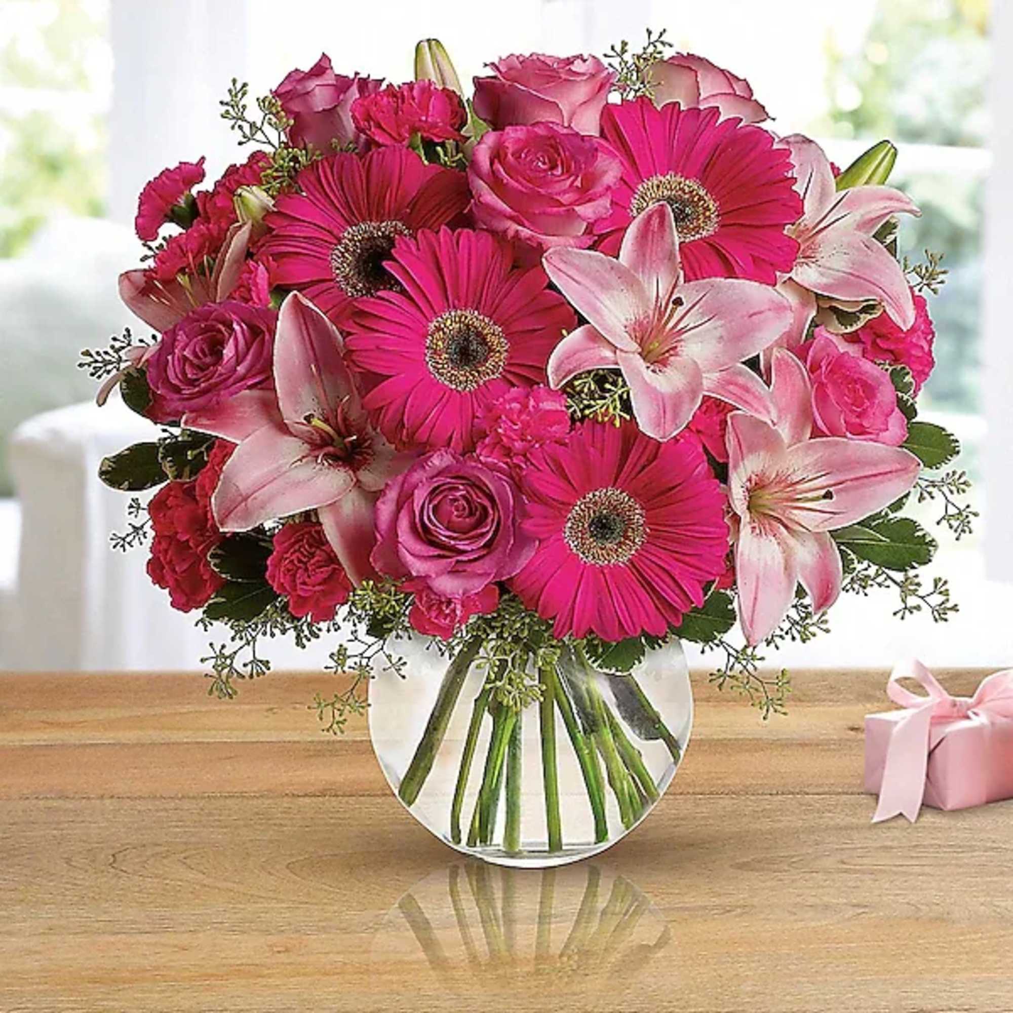 Pink gerberas, roses, lilies, and carnations in a clear glass vase