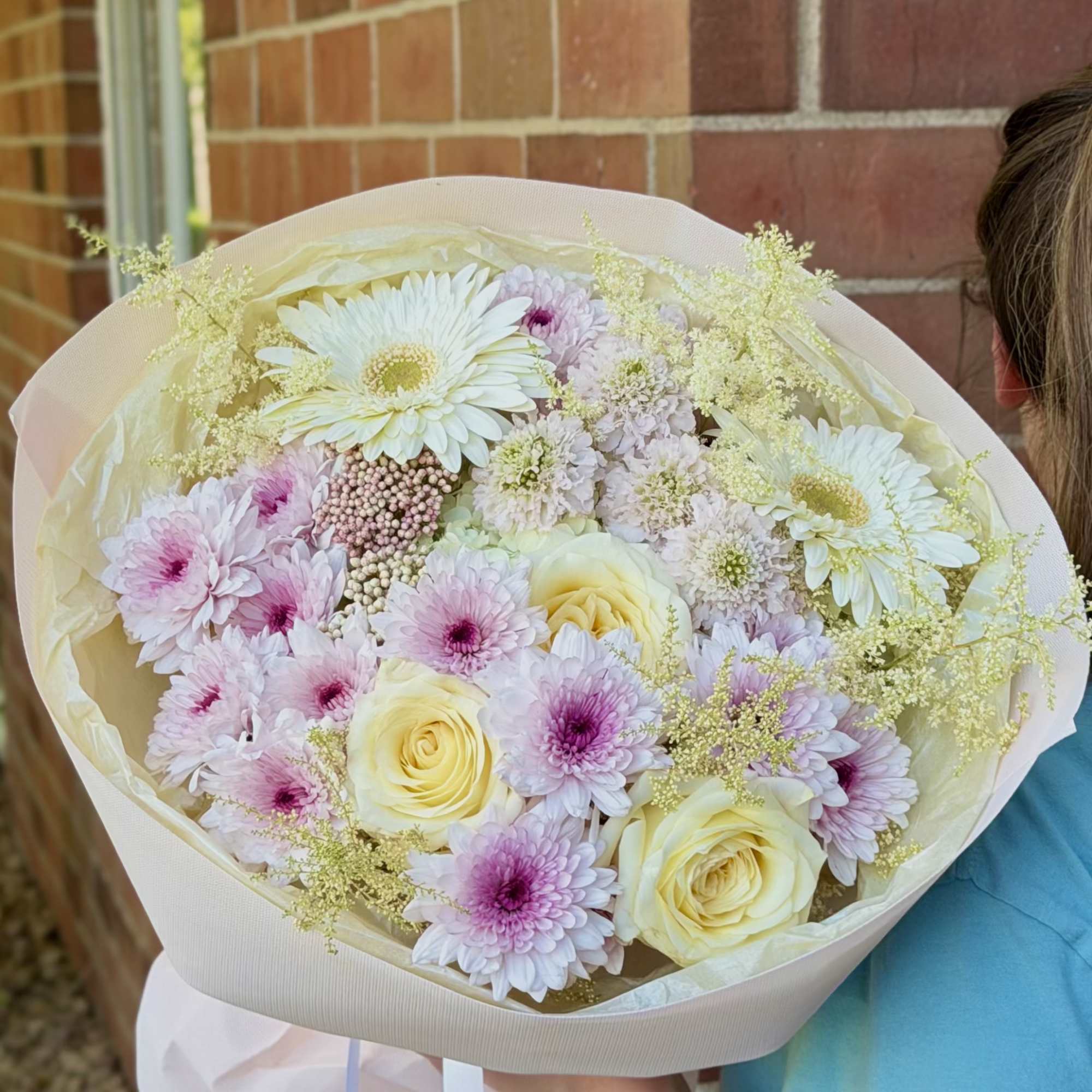 Creamy pale yellow and soft pink roses mingle with lavender and blush
