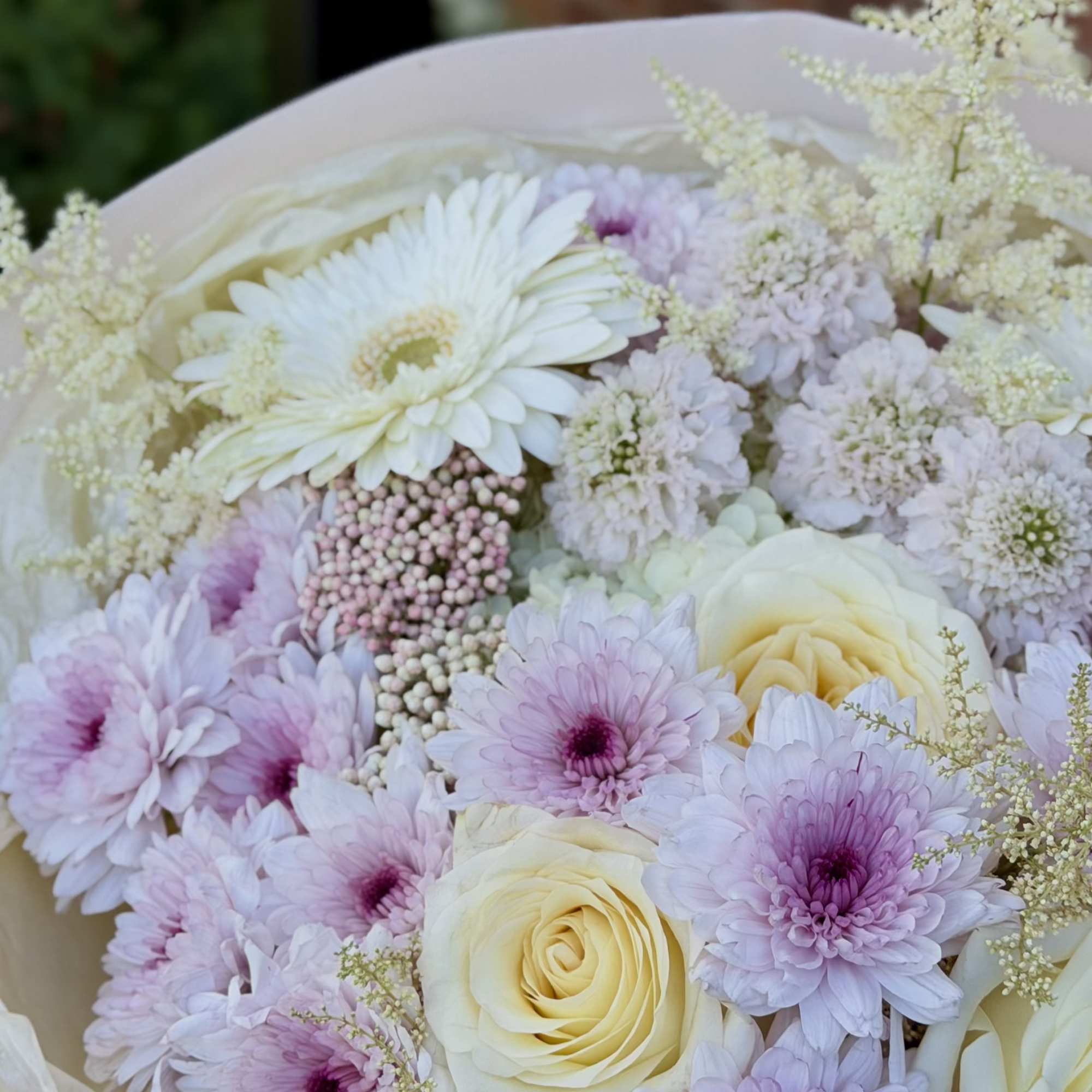 Creamy pale yellow and soft pink roses mingle with lavender and blush
