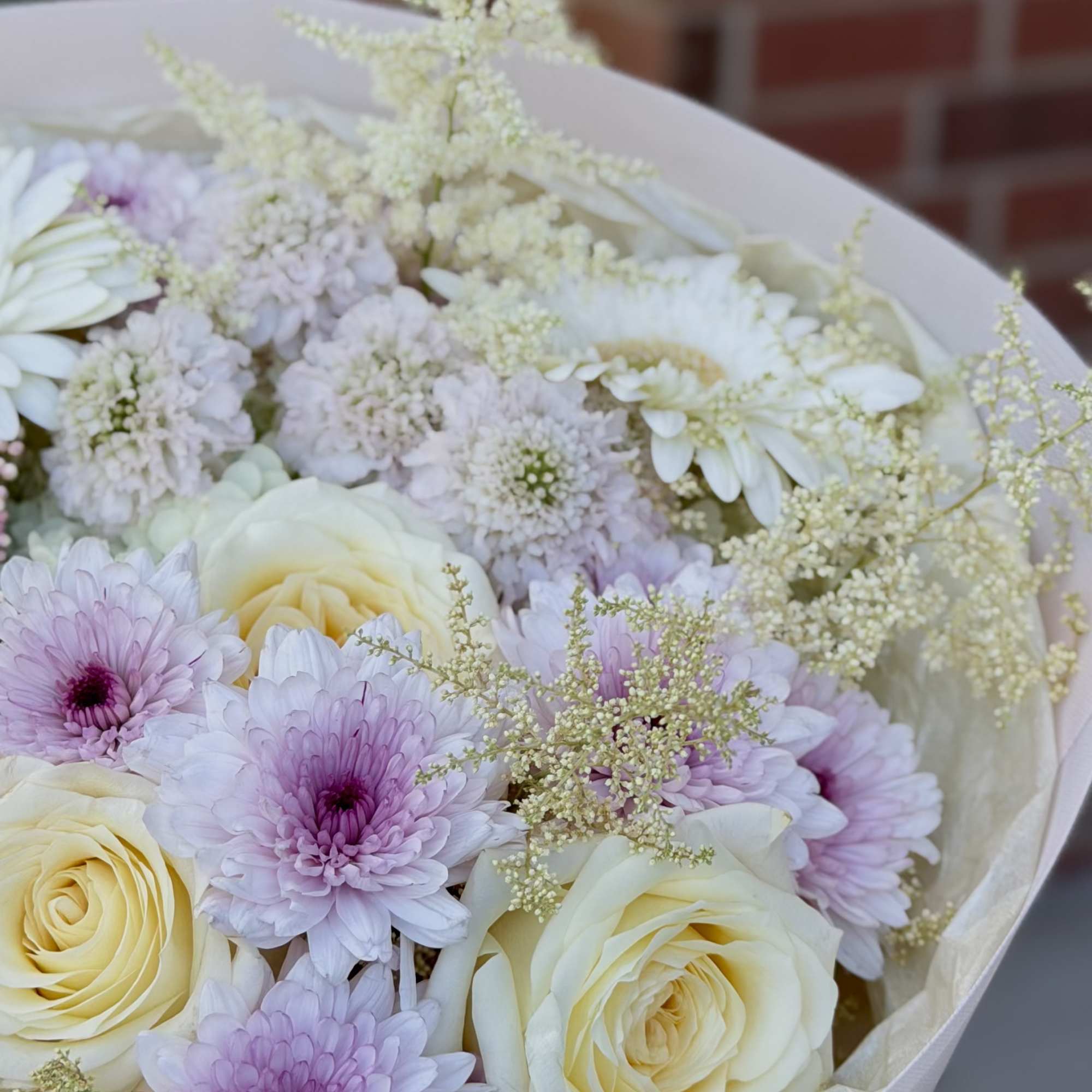 Creamy pale yellow and soft pink roses mingle with lavender and blush