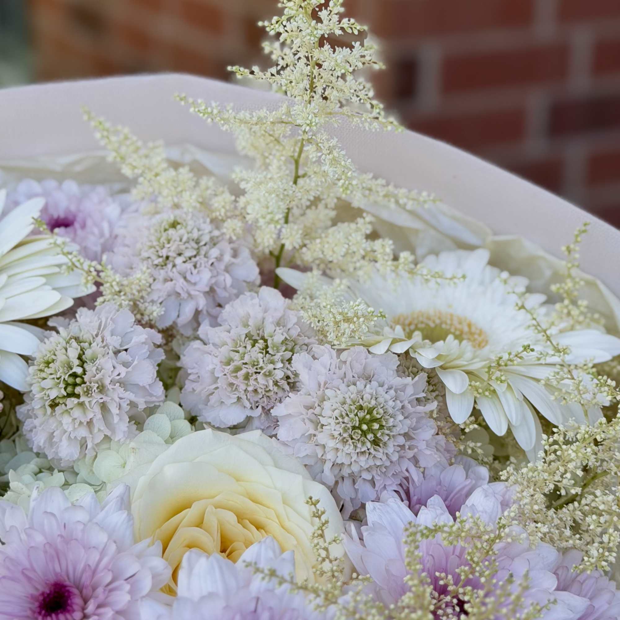 Creamy pale yellow and soft pink roses mingle with lavender and blush
