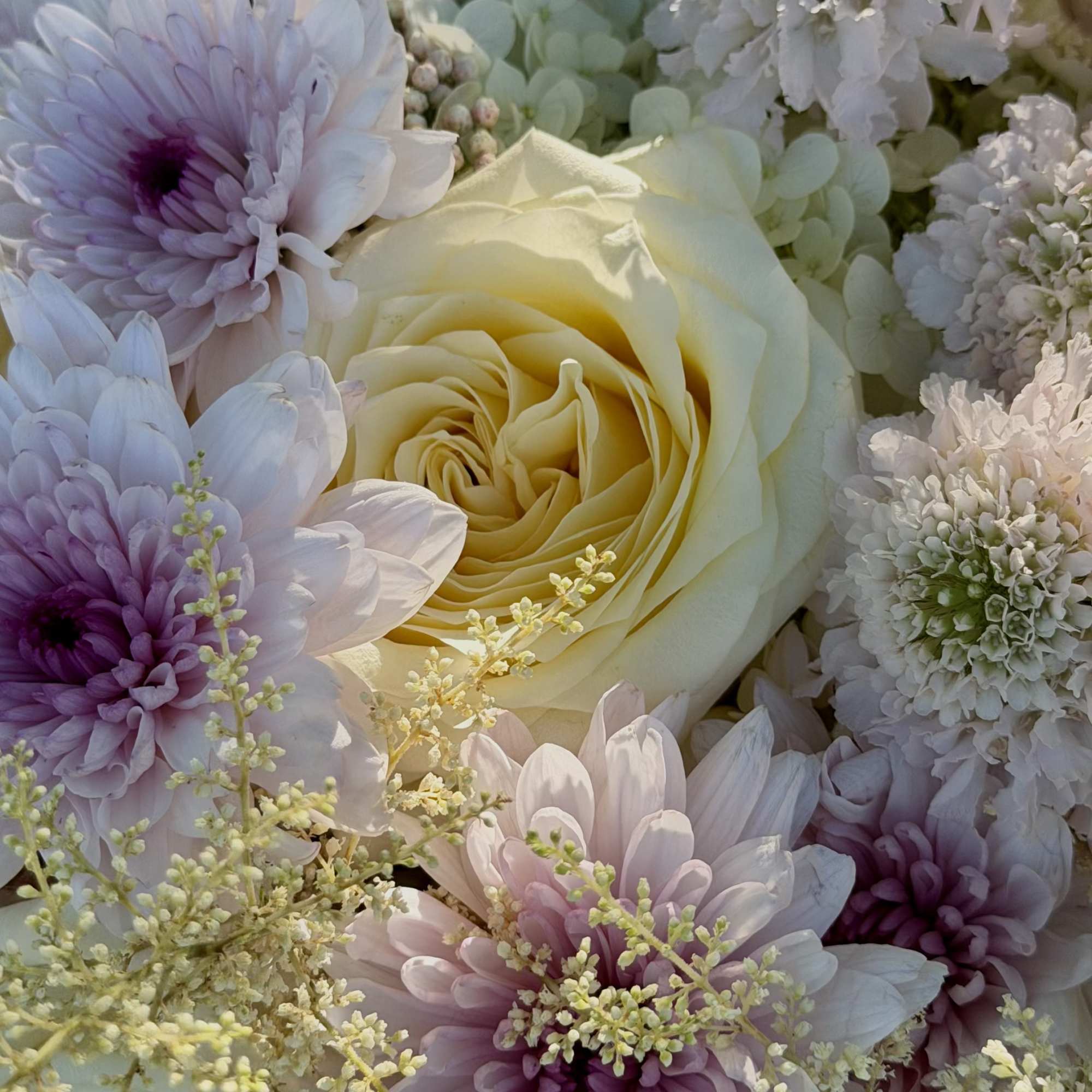 Creamy pale yellow and soft pink roses mingle with lavender and blush