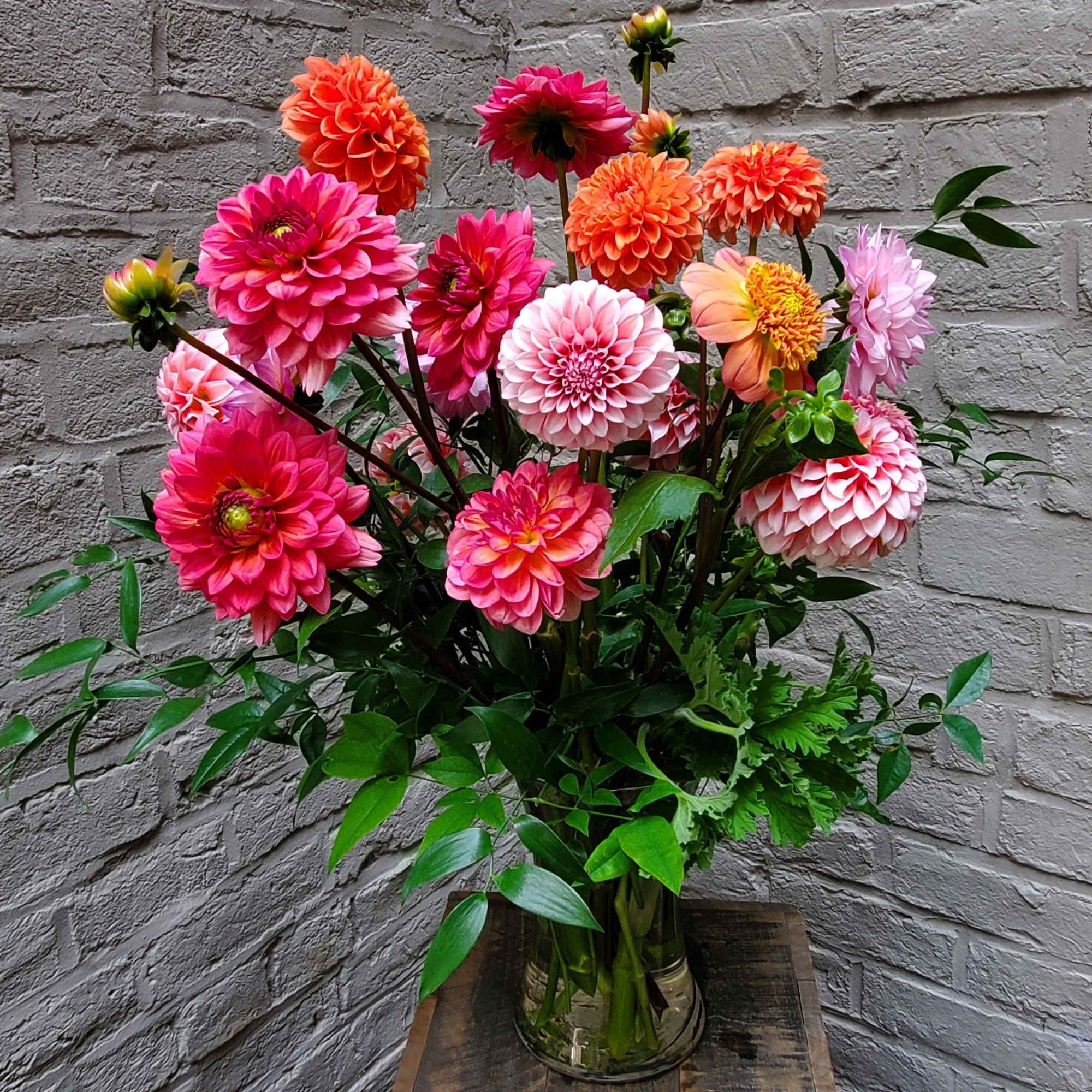 Bouquet of pink, orange, and peach dahlias in a glass vase