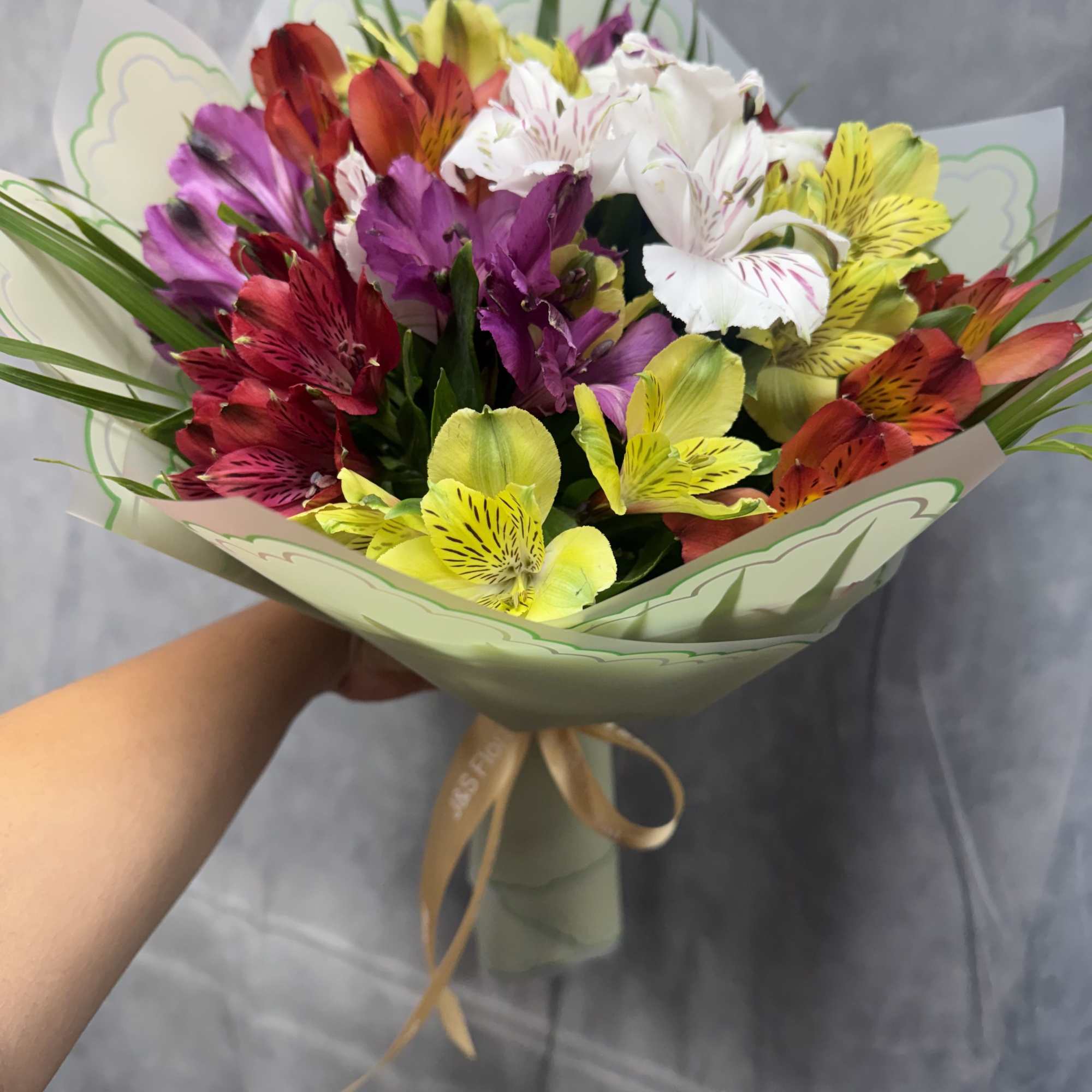 Colorful bouquet of alstroemeria flowers wrapped in pale green paper