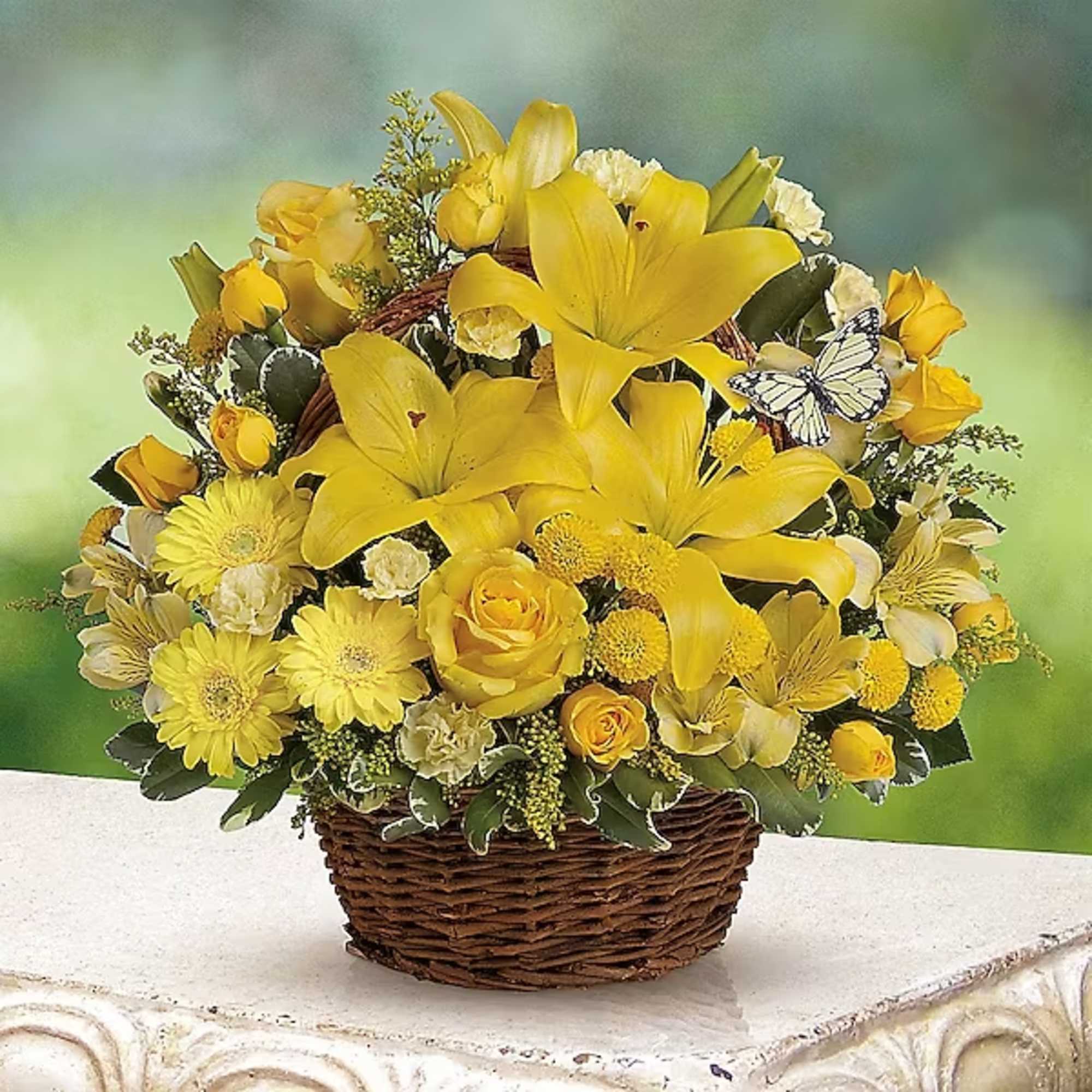 Yellow floral arrangement in a woven basket with roses and lilies