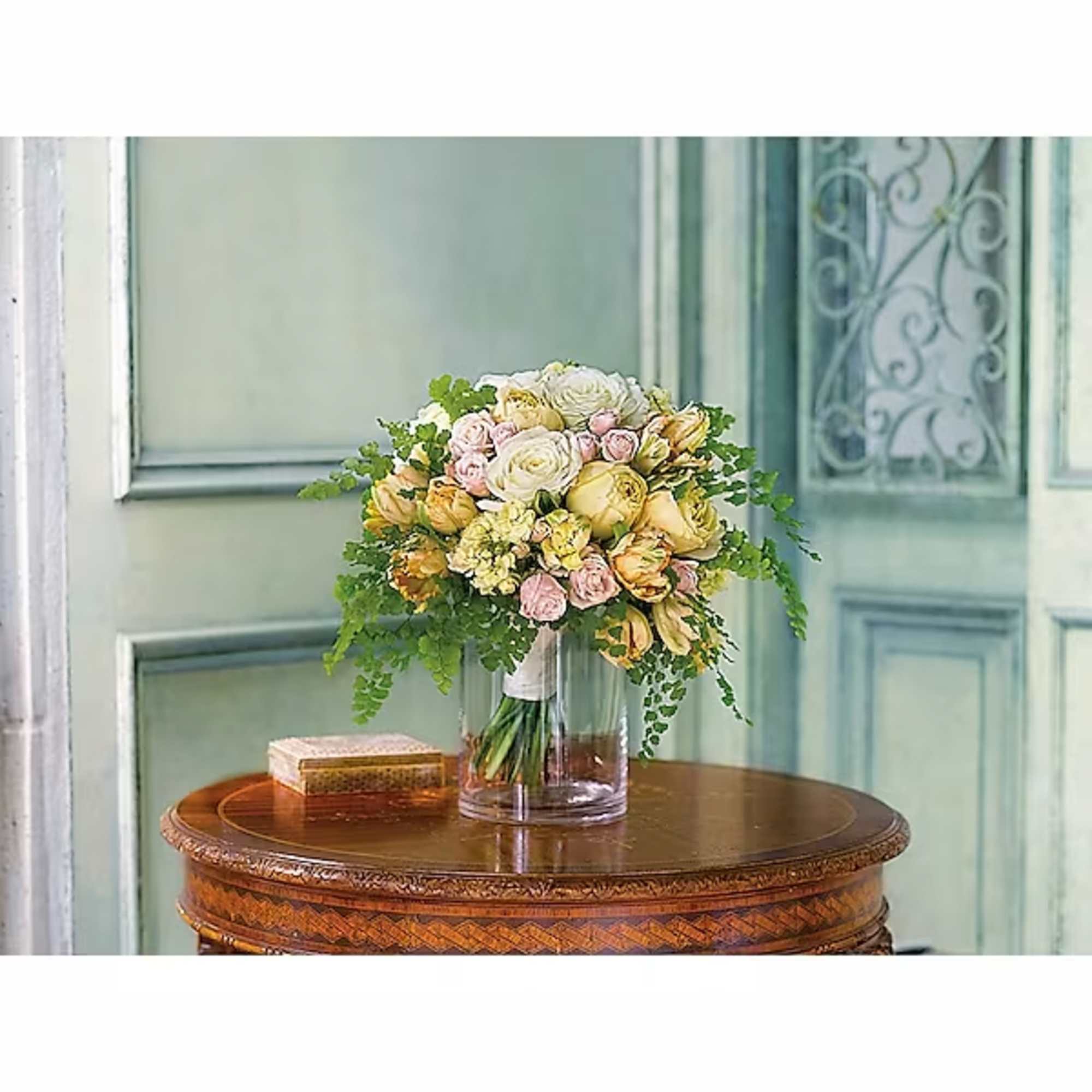 Bouquet of pale roses and yellow flowers in a clear glass vase