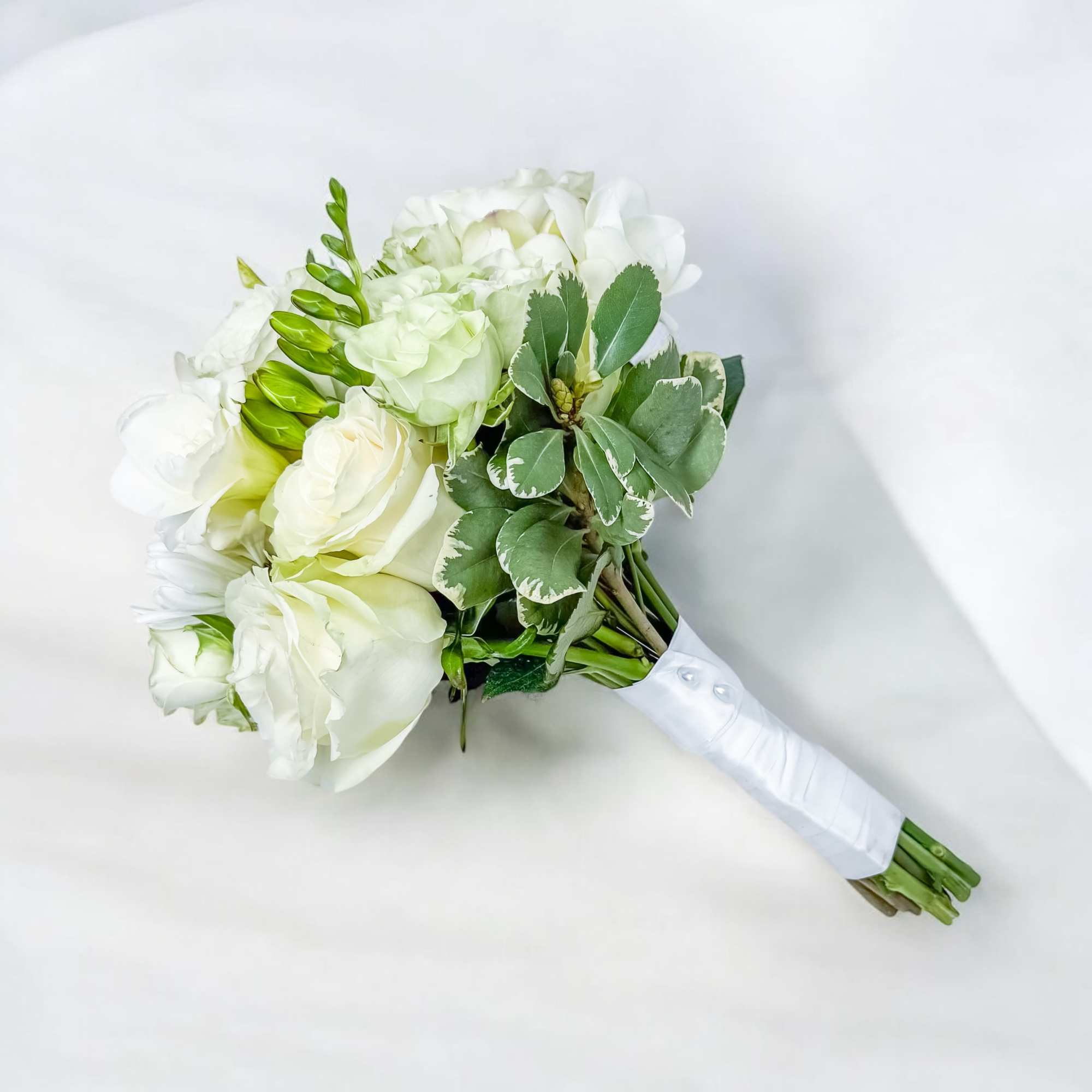 White rose bouquet with green foliage and wrapped stems