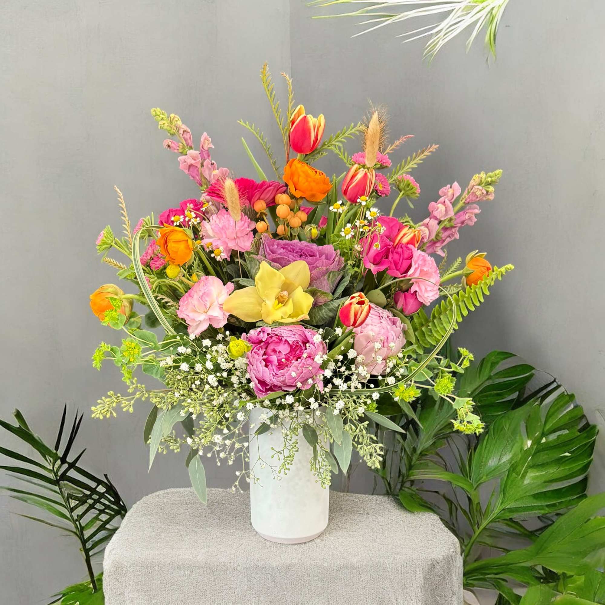 Colorful mixed bouquet in a white vase with tulips and peonies
