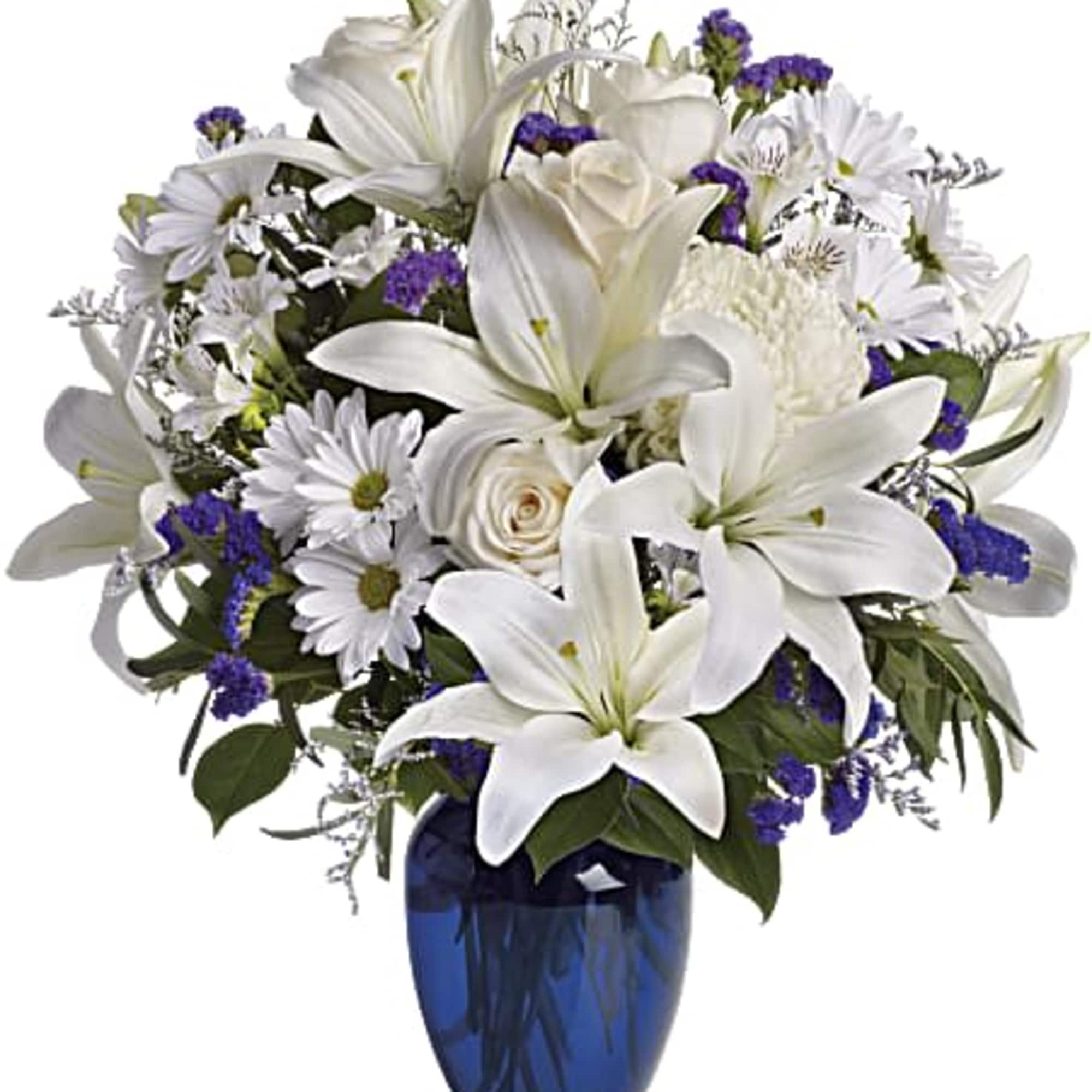 White lilies and daisies with purple accents in a blue vase