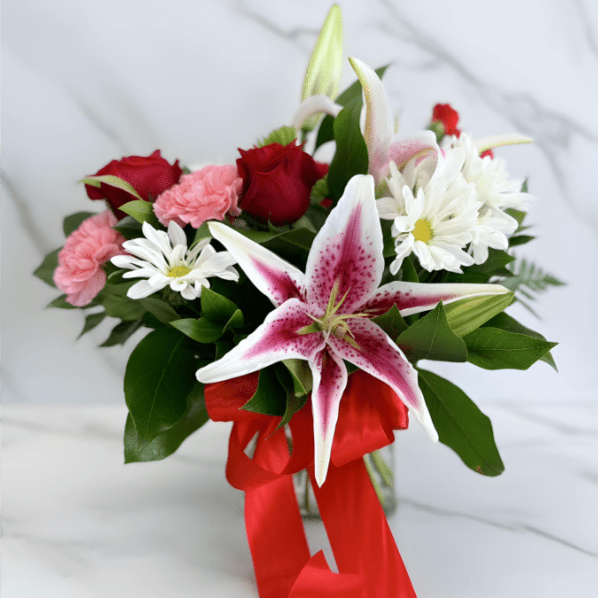 Bouquet of red roses, pink carnations, white daisies, and a pink stargazer lily with a red ribbon