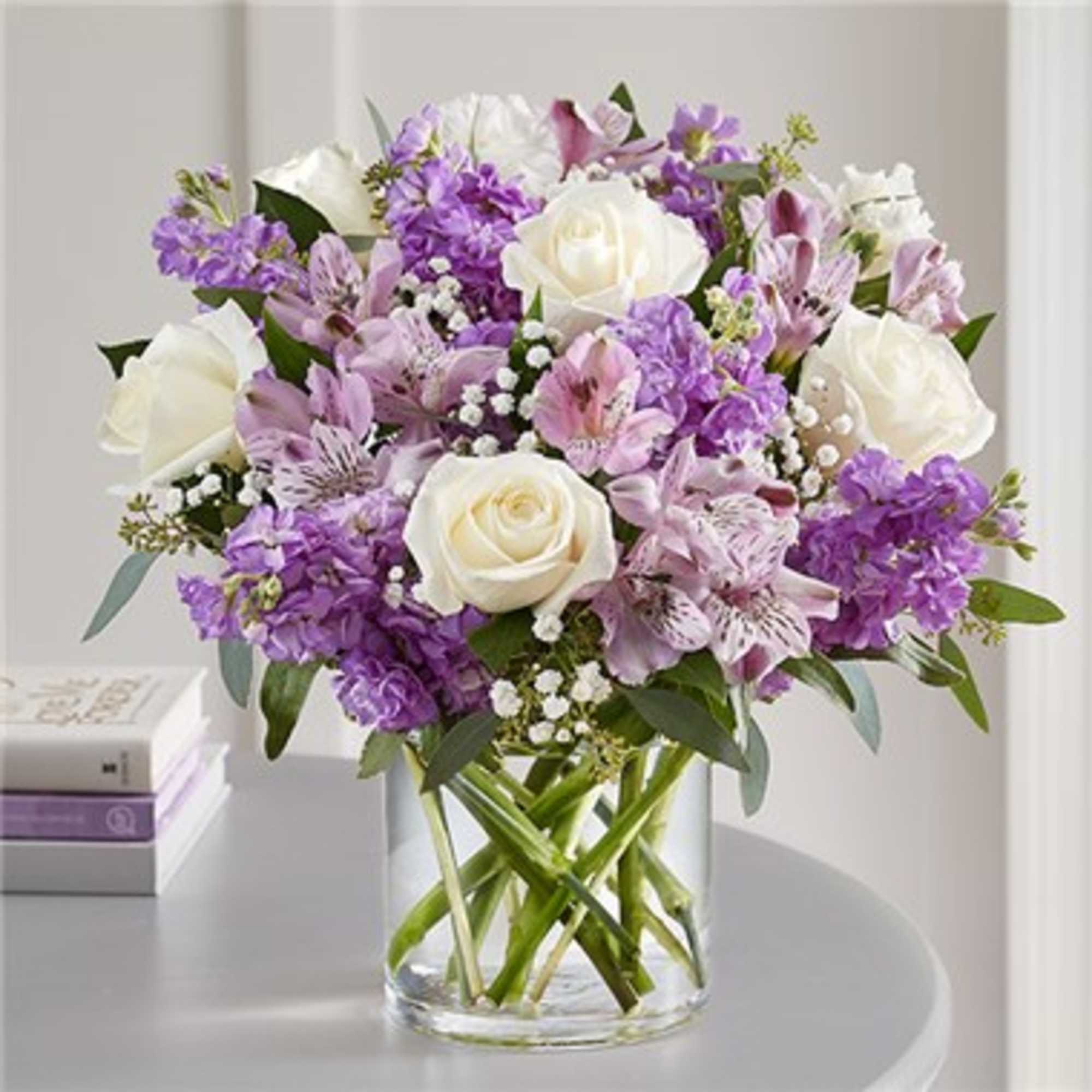 Bouquet of white roses, purple flowers, and pink alstroemeria in a glass vase