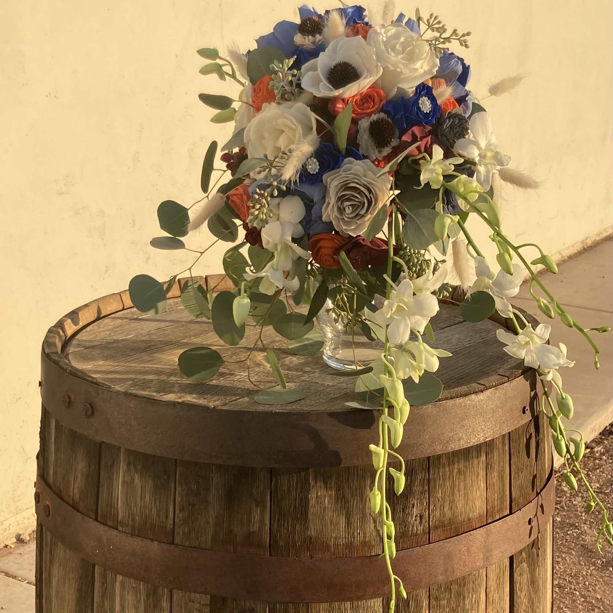Mixed bouquet of blue, white, and orange flowers in a clear vase