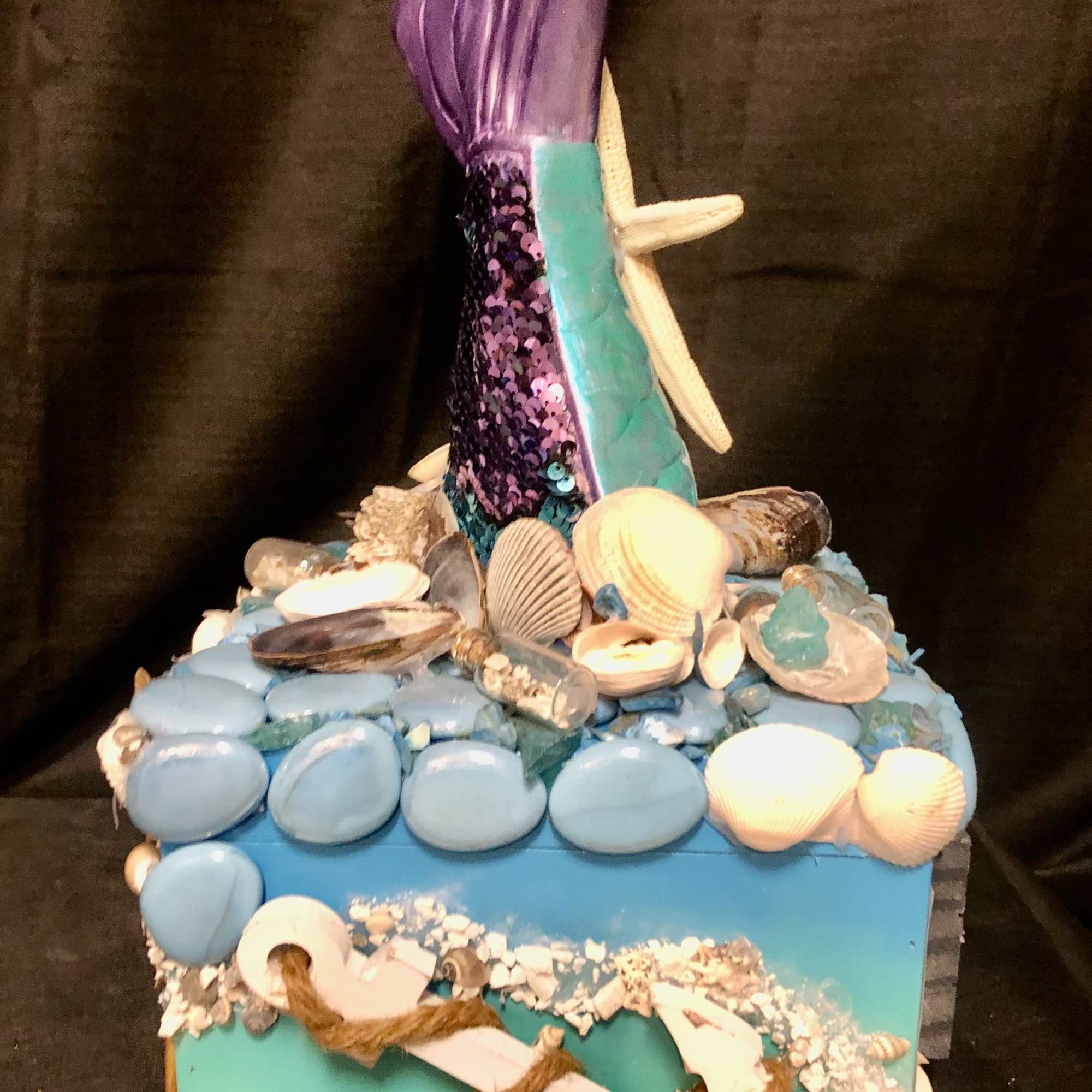 Decorative mermaid-themed box with shells and a purple tail topper