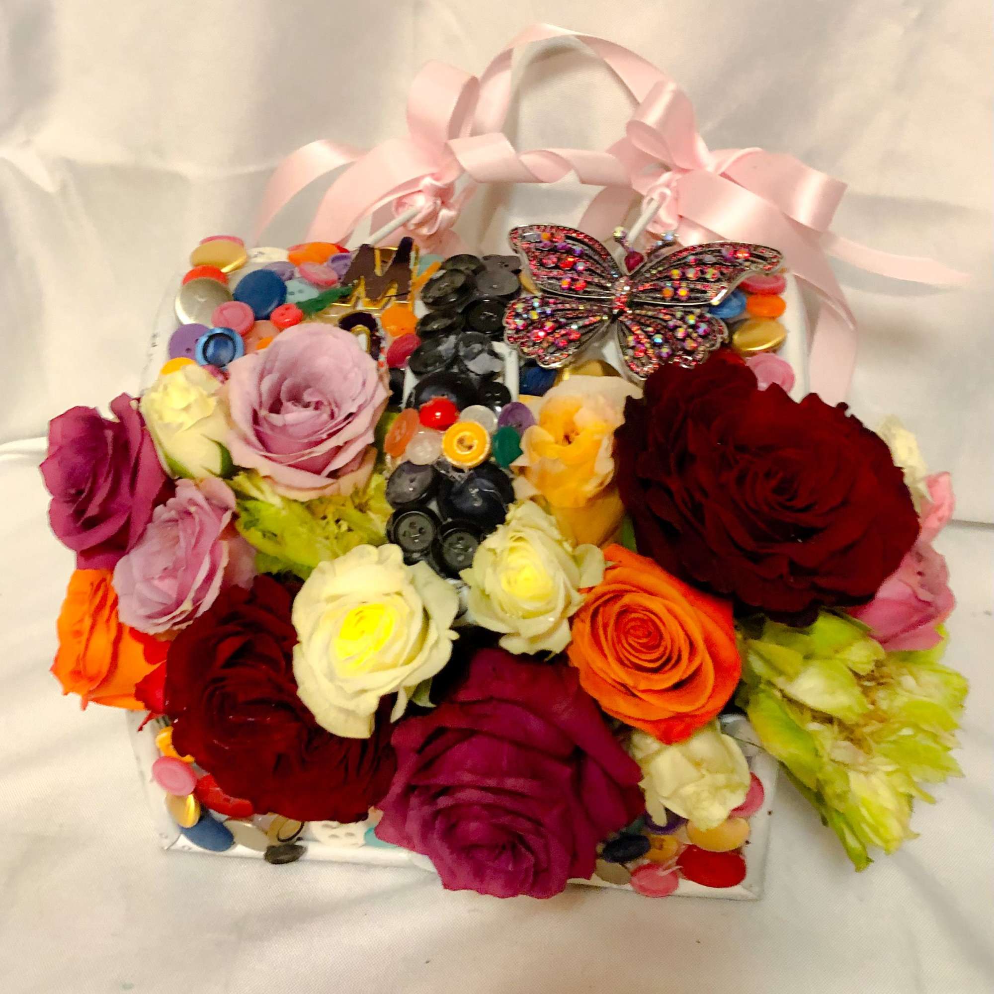Colorful rose arrangement in a decorated gift box with pink ribbon handles