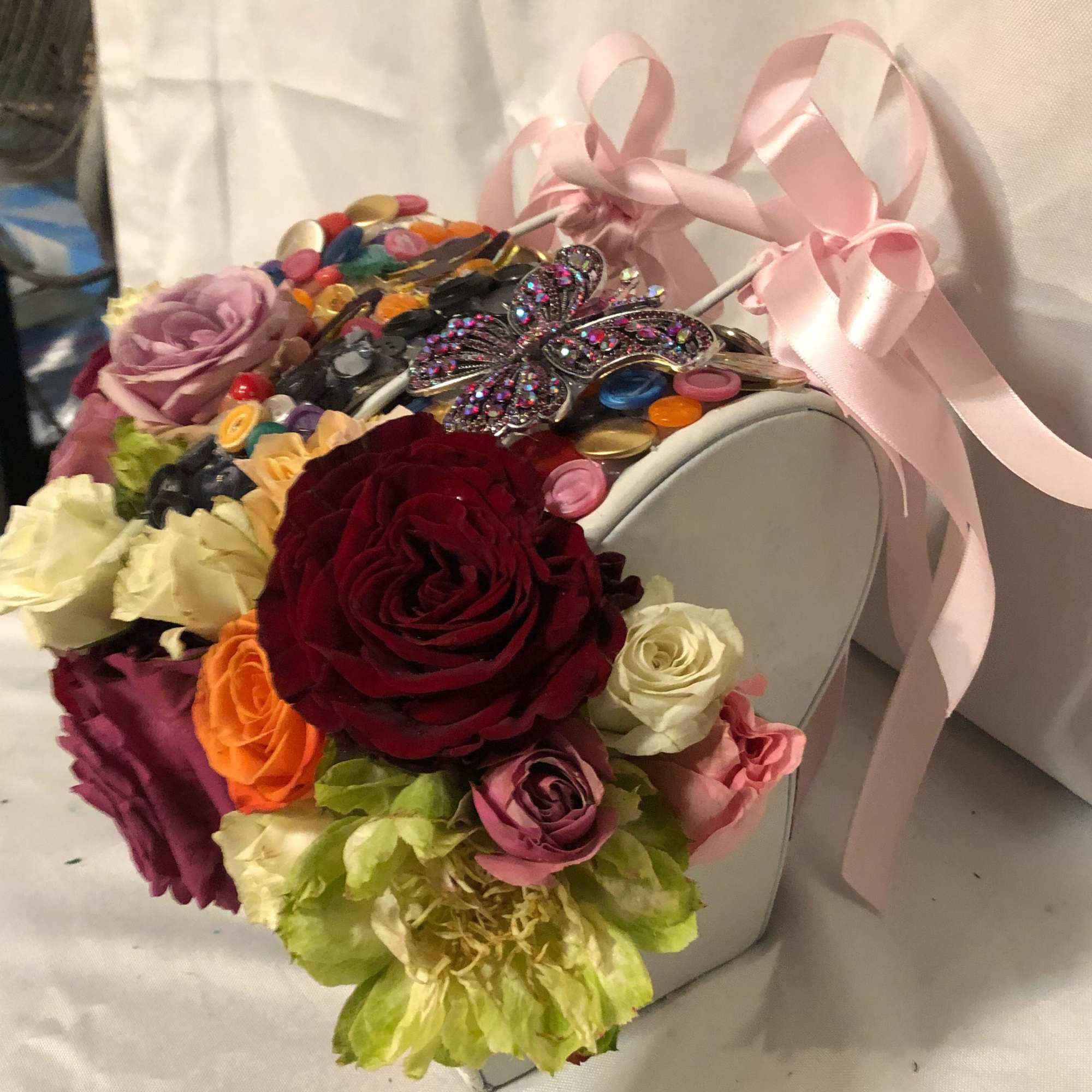 Heart-shaped box filled with colorful roses and a jeweled butterfly decoration