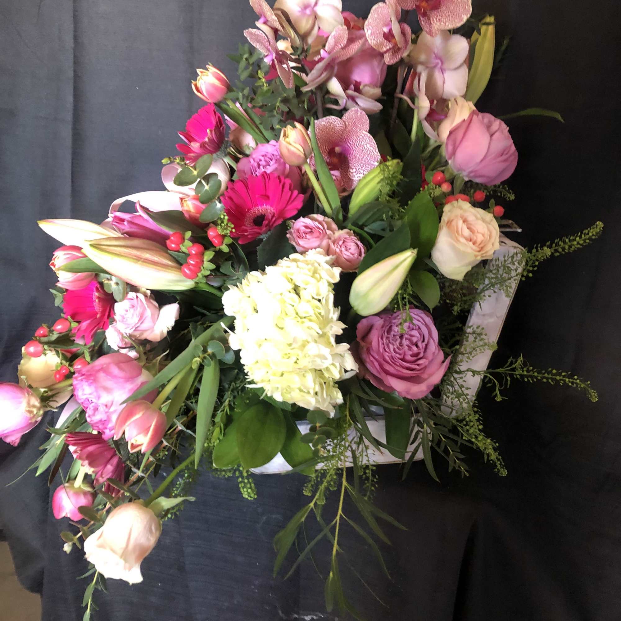 Asymmetrical pink and white flower arrangement in a white heart-shaped box