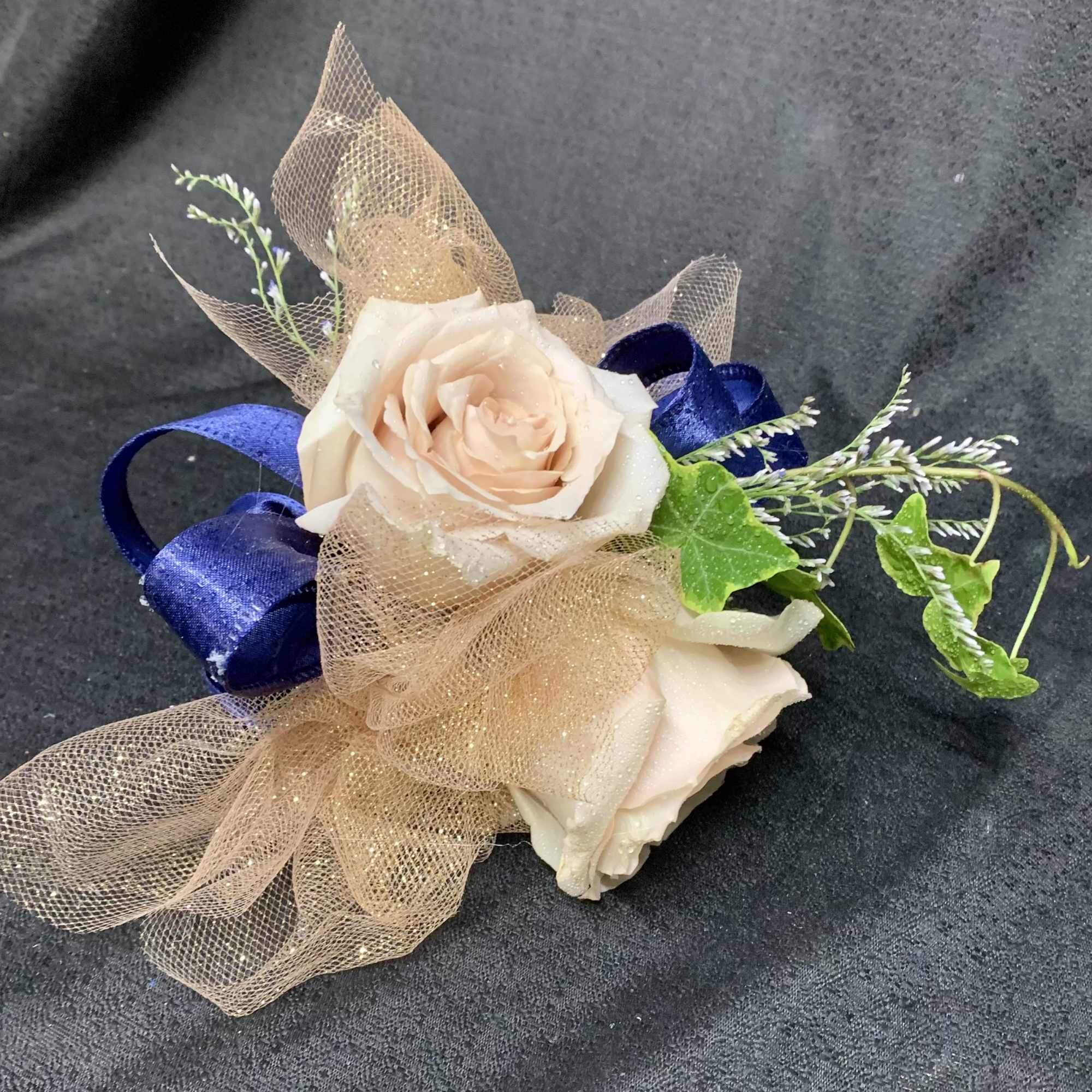 Two pale roses with blue ribbon and tan mesh wrap