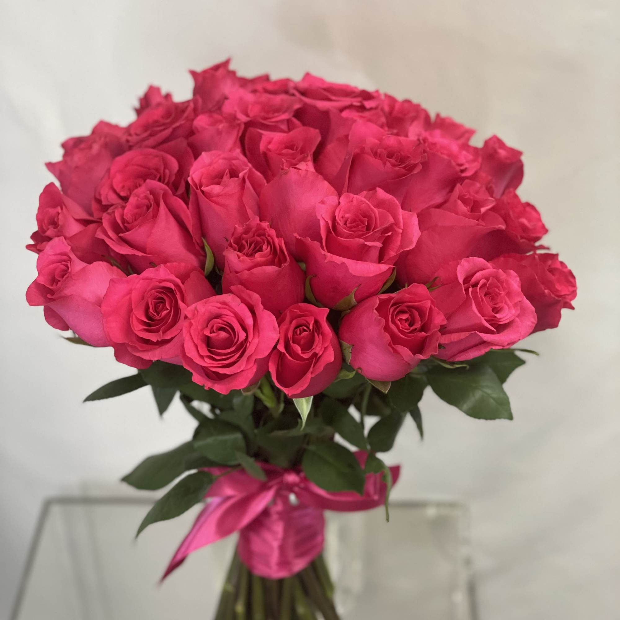 Bouquet of bright pink roses tied with a pink ribbon