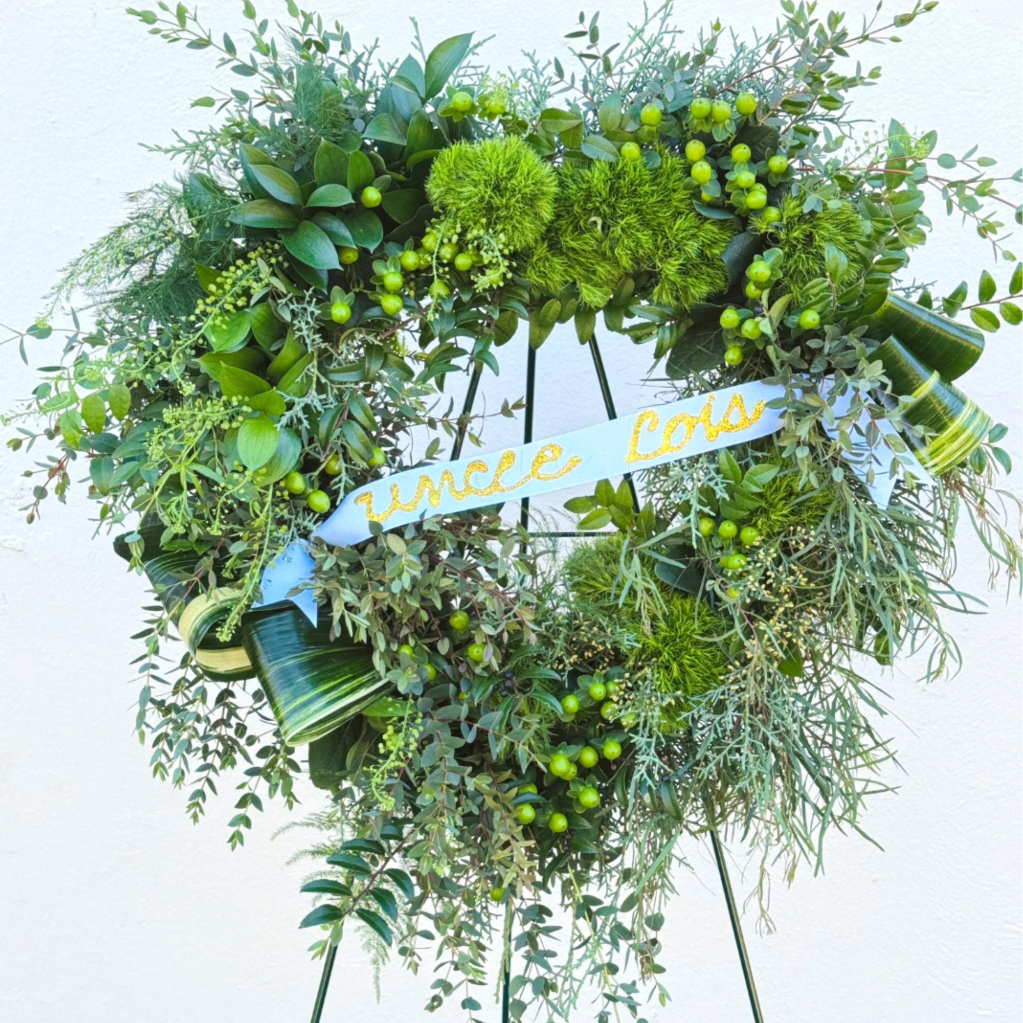 Heart-shaped green wreath on an easel with a blue ribbon
