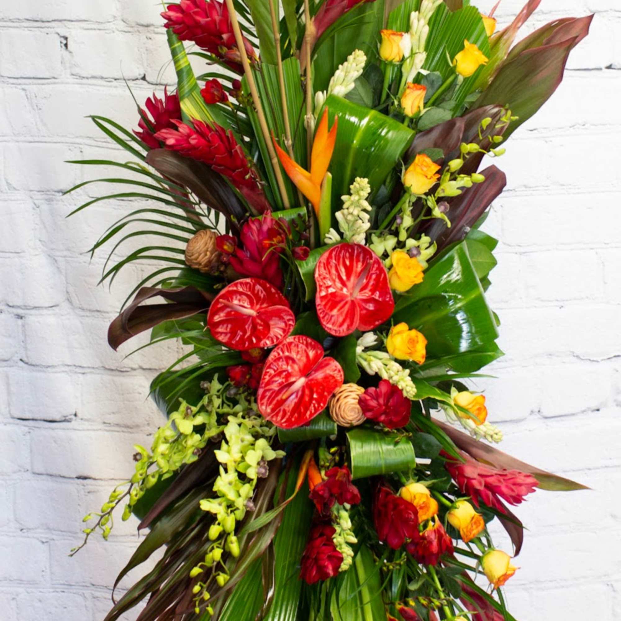 Tall tropical floral spray with red and yellow blooms on a stand
