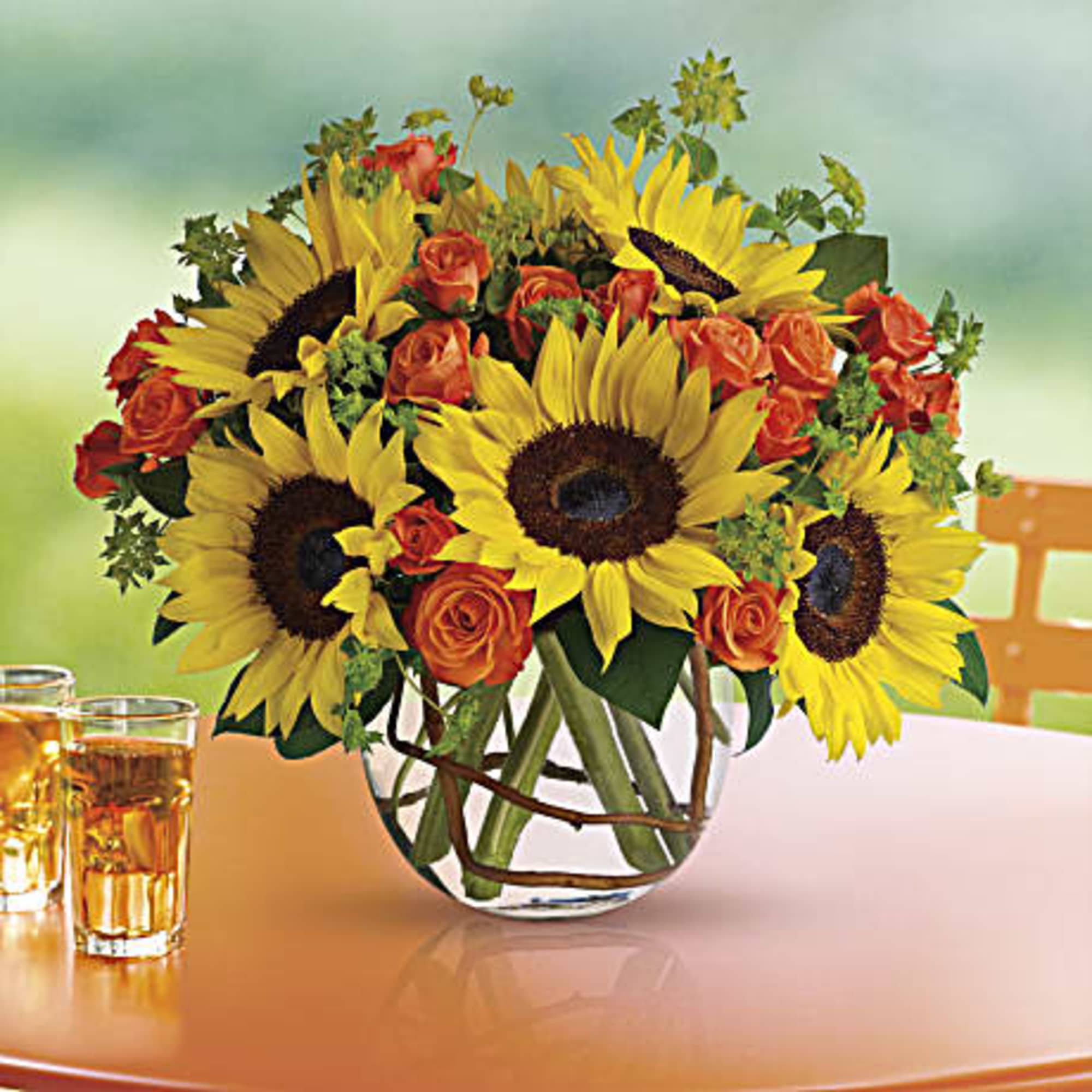 Bouquet of sunflowers and orange roses in a glass vase