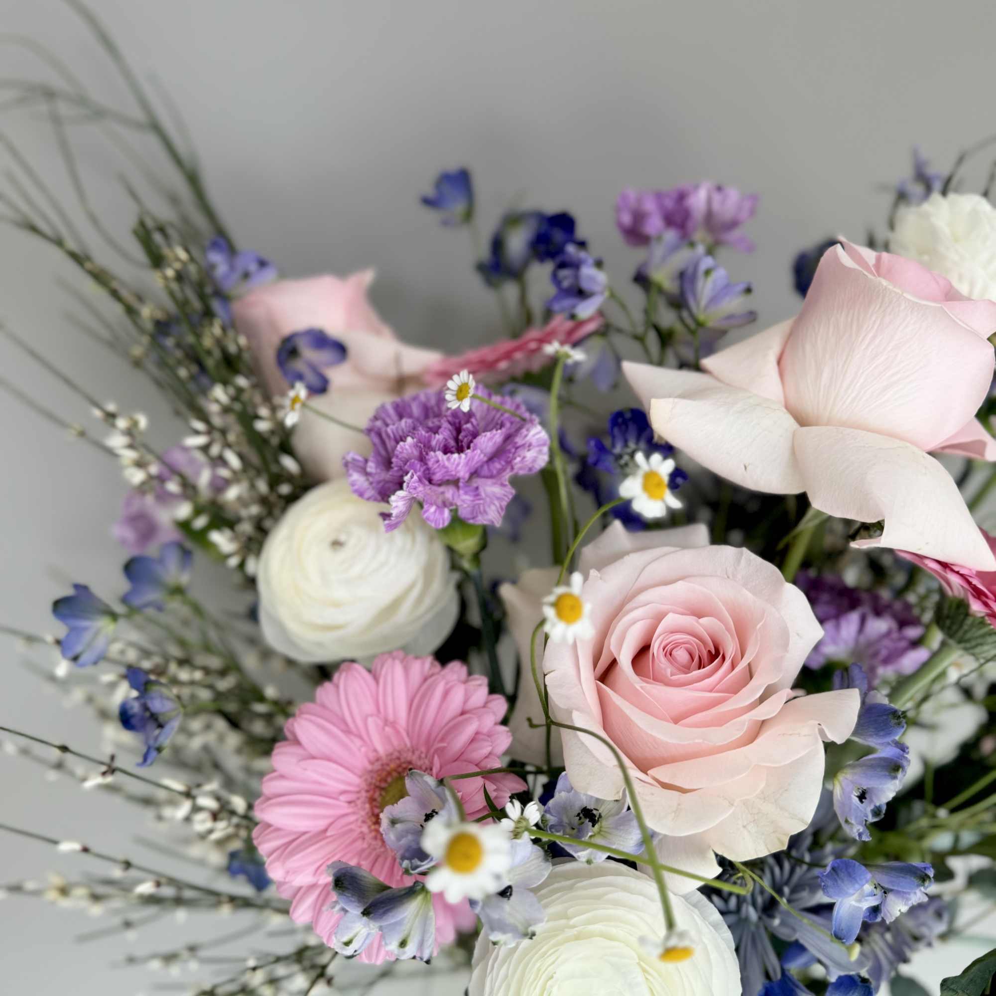 Bouquet of pink roses, white ranunculus, and purple flowers