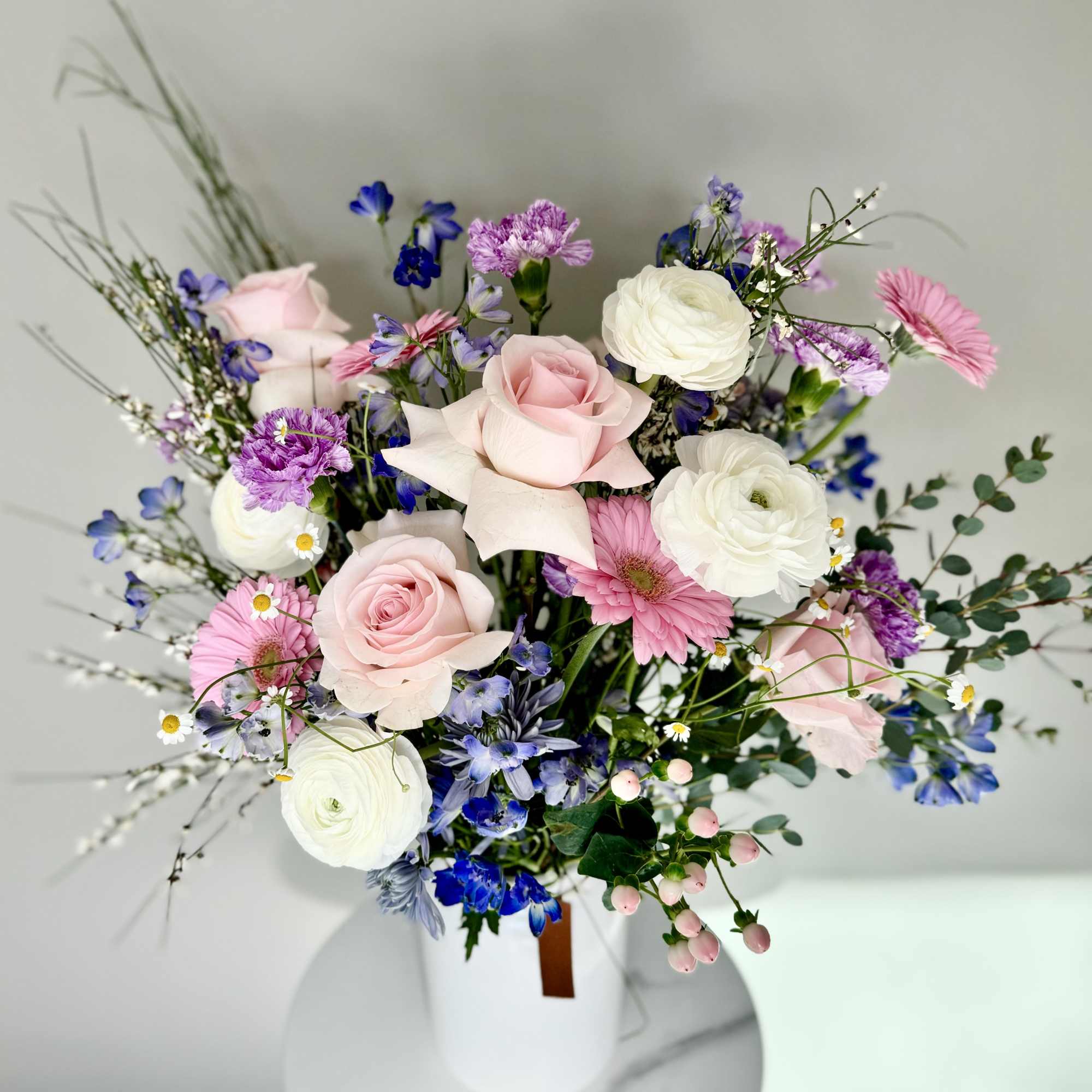 Mixed bouquet of pink and white flowers in a white vase