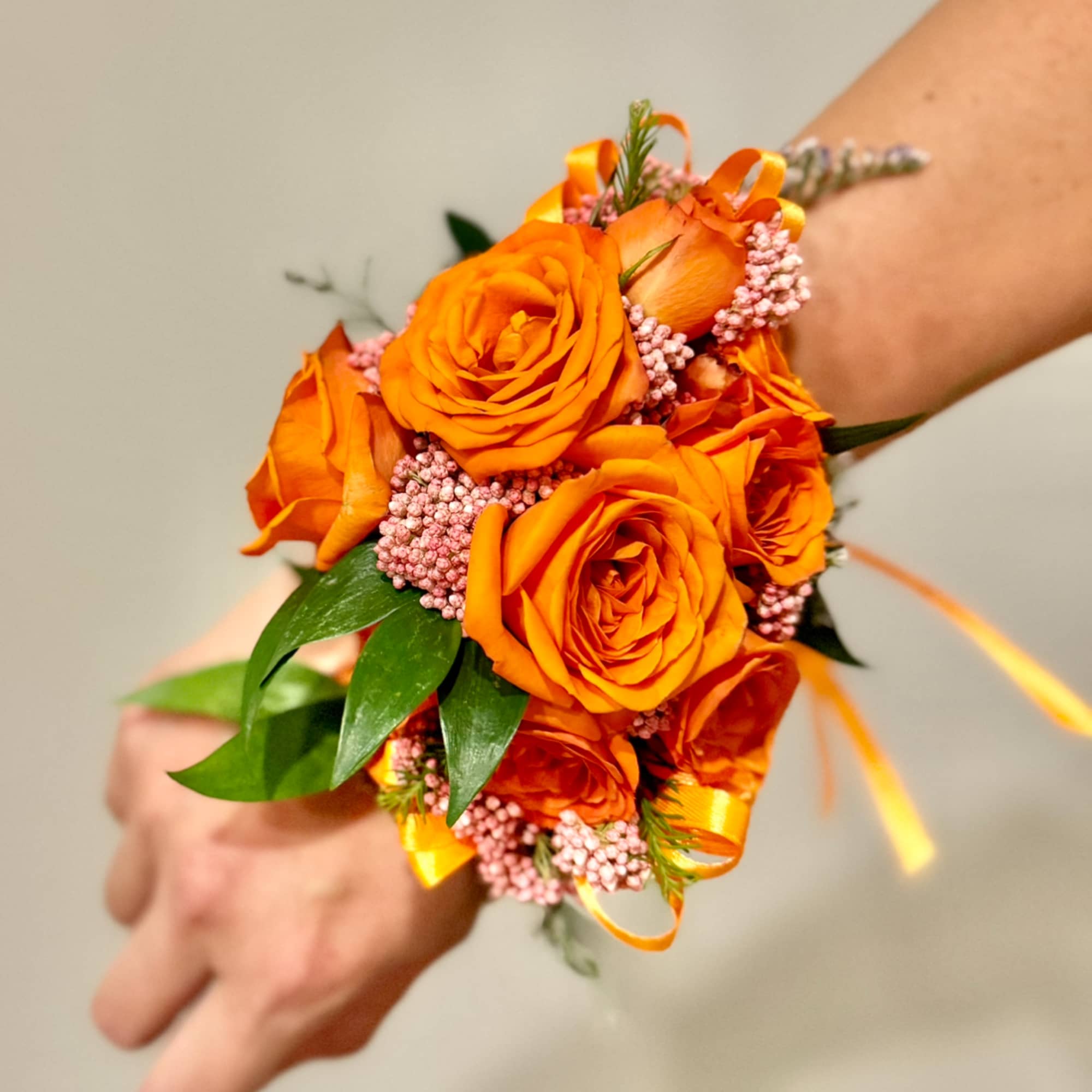 Orange rose wrist corsage with pink filler and ribbon