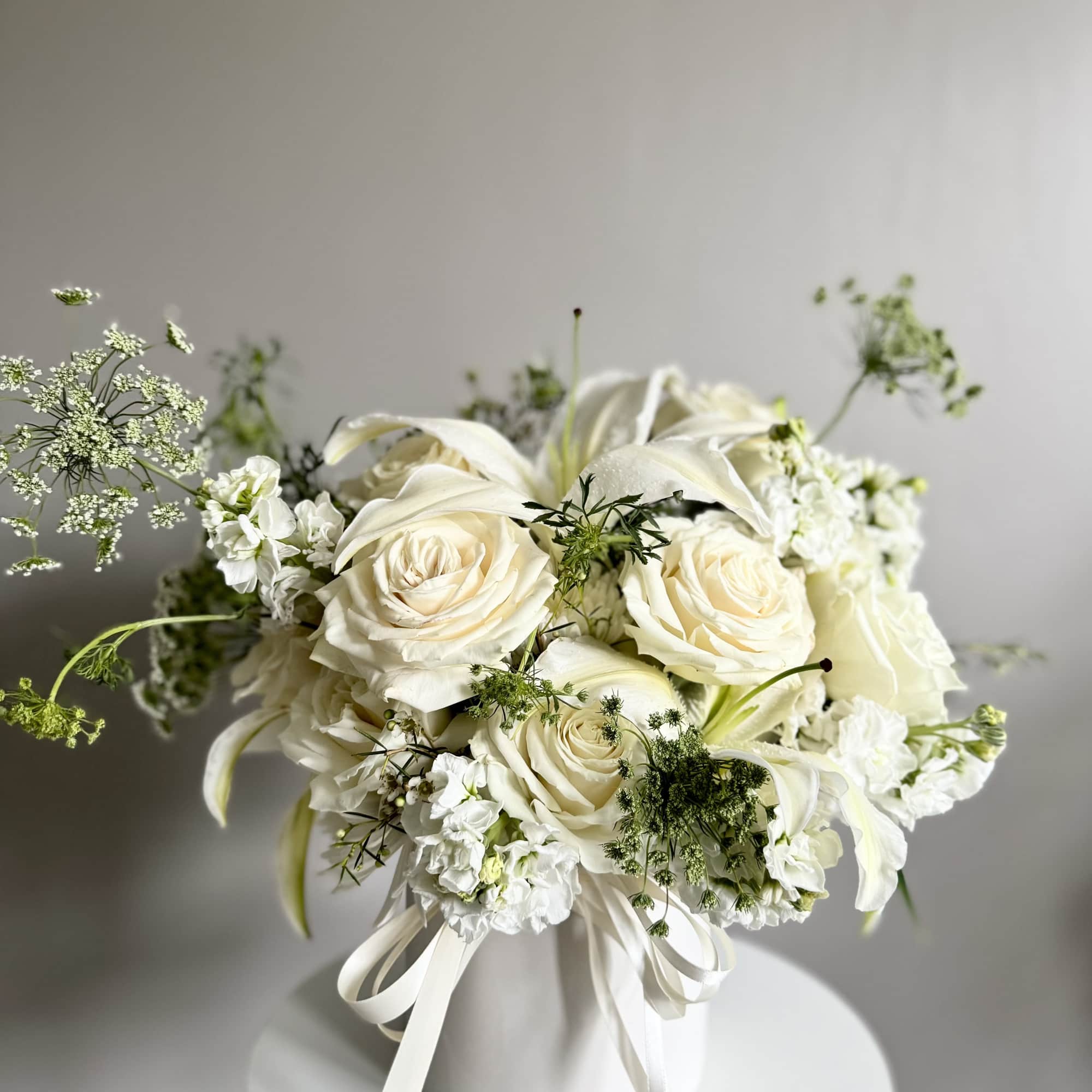 White rose and lily bouquet in a white hatbox with ribbon