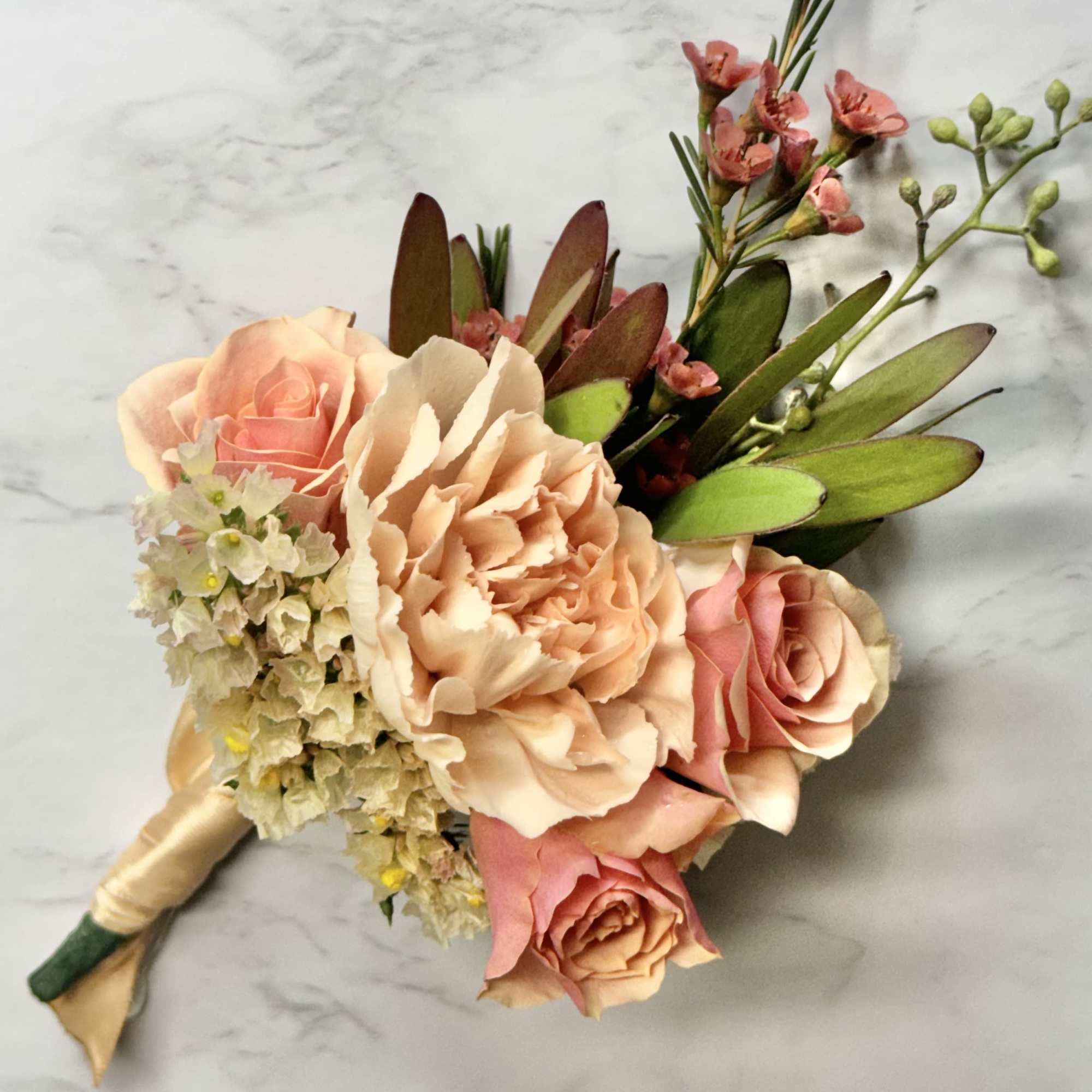 Hand-tied bouquet of peach and pink roses with small filler flowers