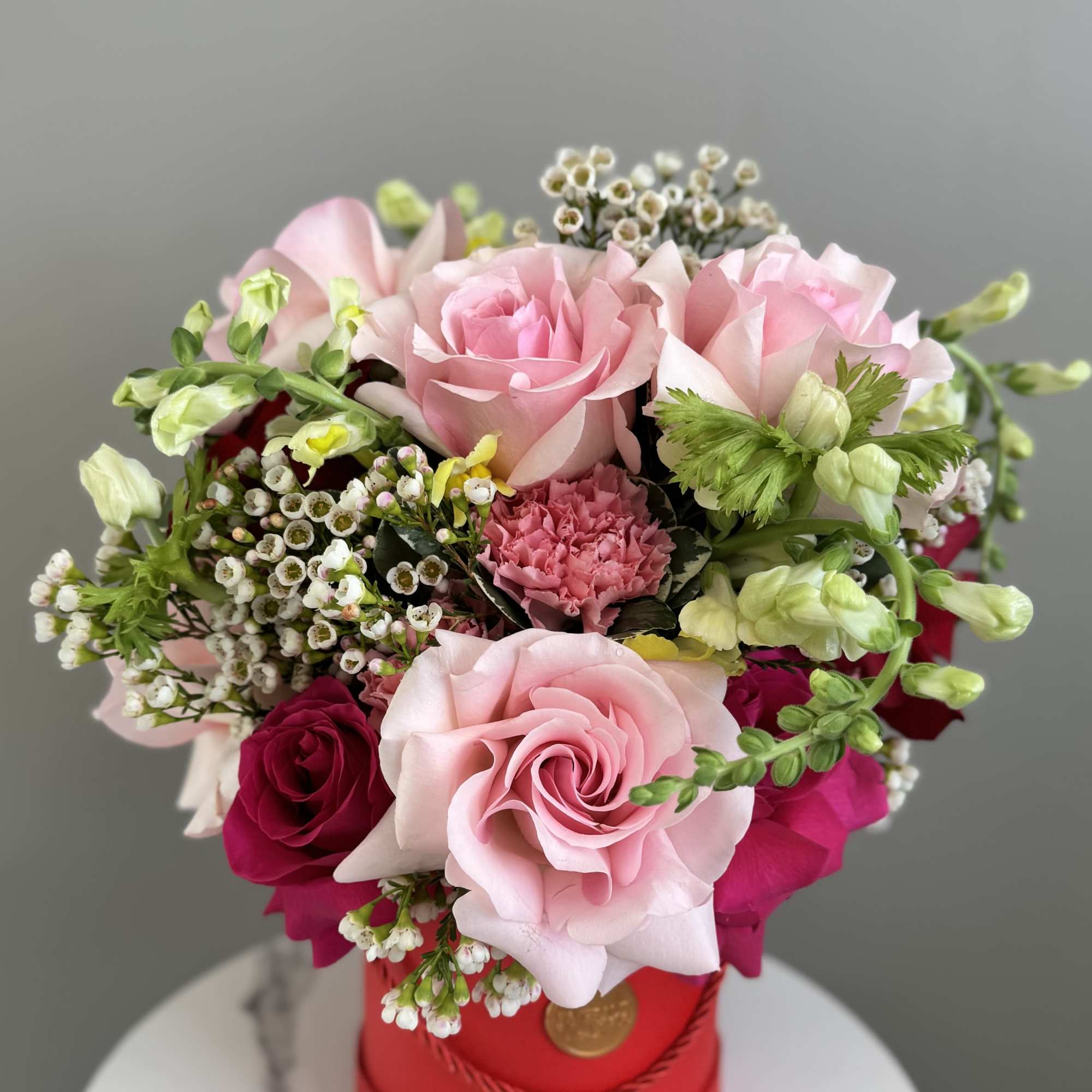 Pink and red rose bouquet in a red hatbox