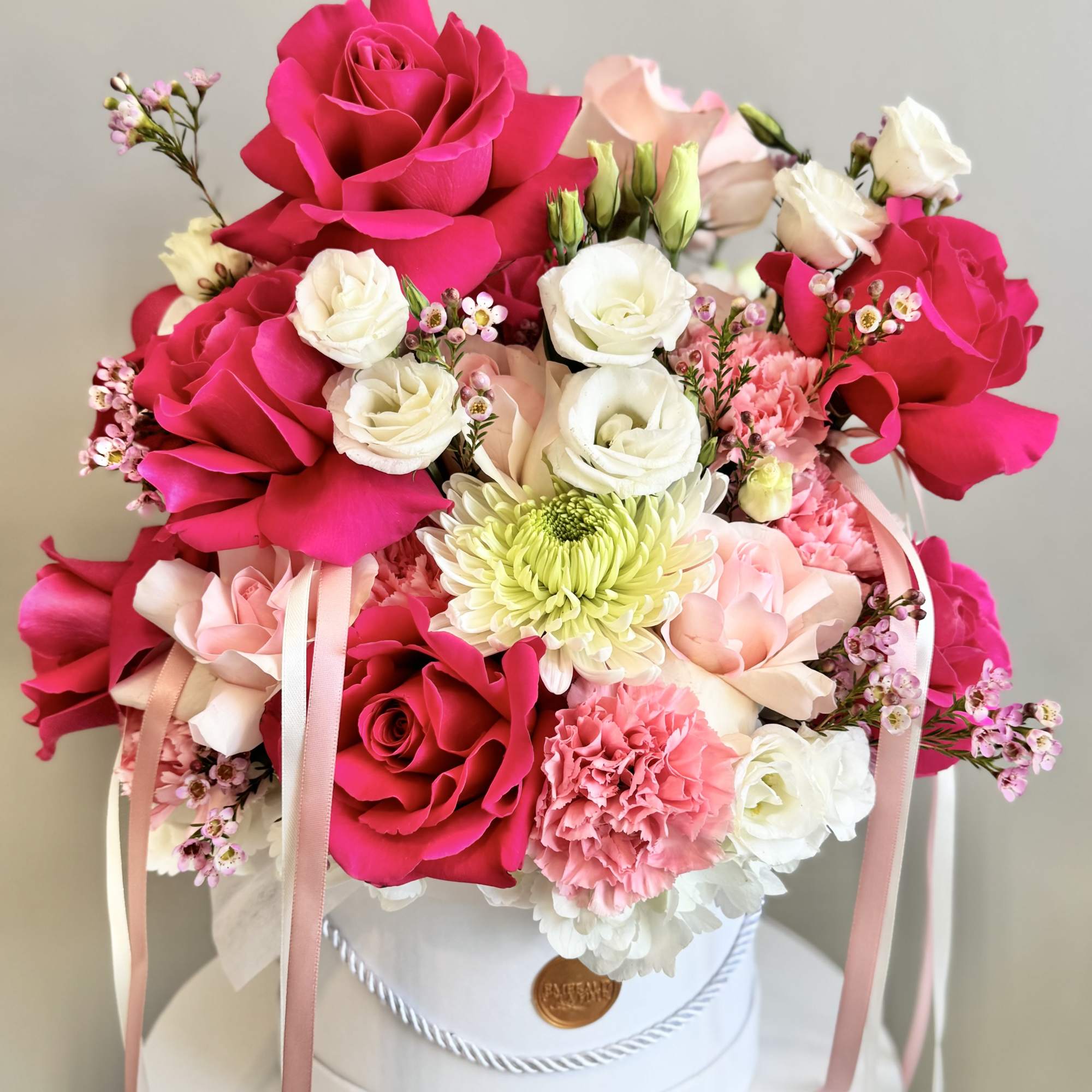 Bouquet of hot pink and white roses with pink carnations in a white hat box