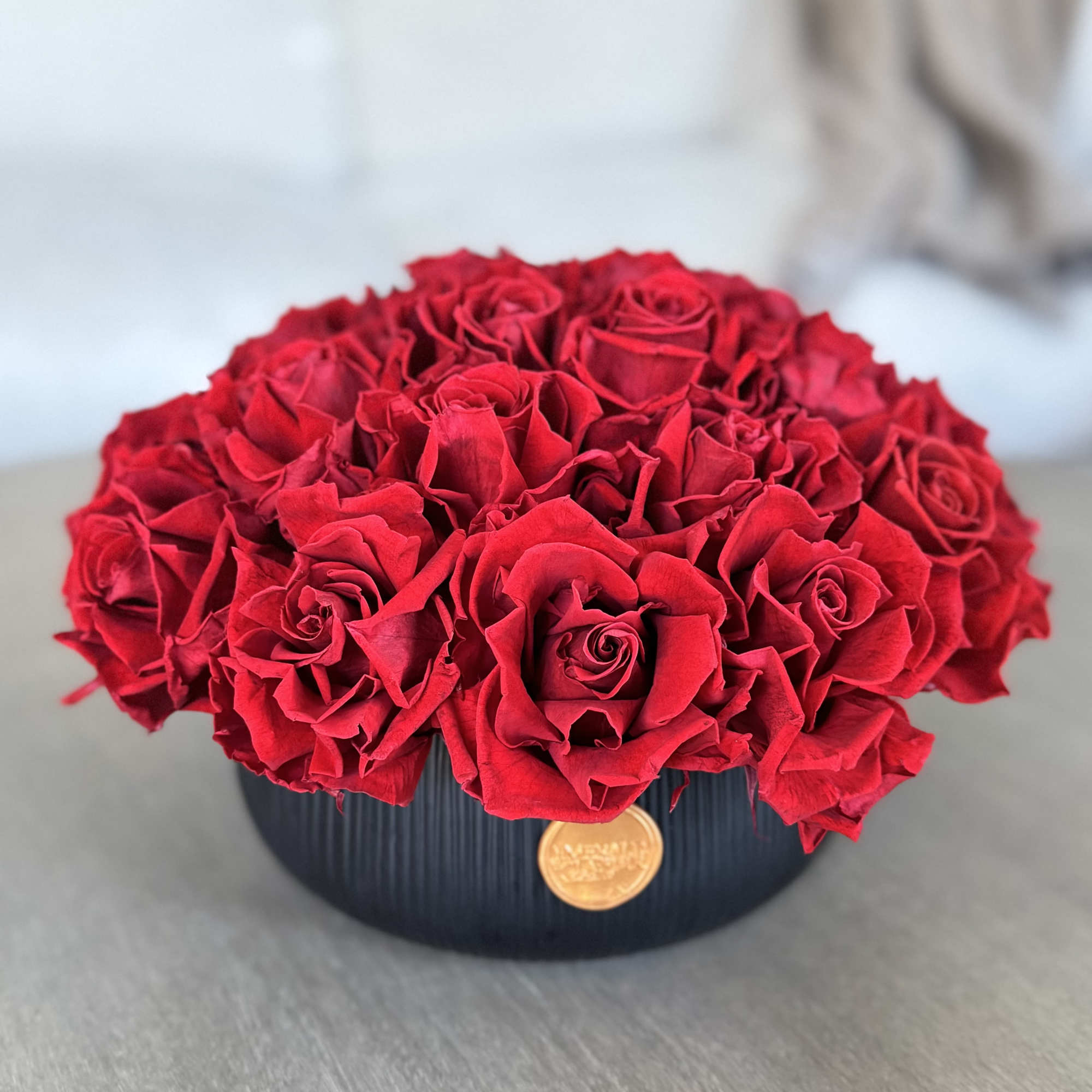 Round arrangement of red roses in a black vase