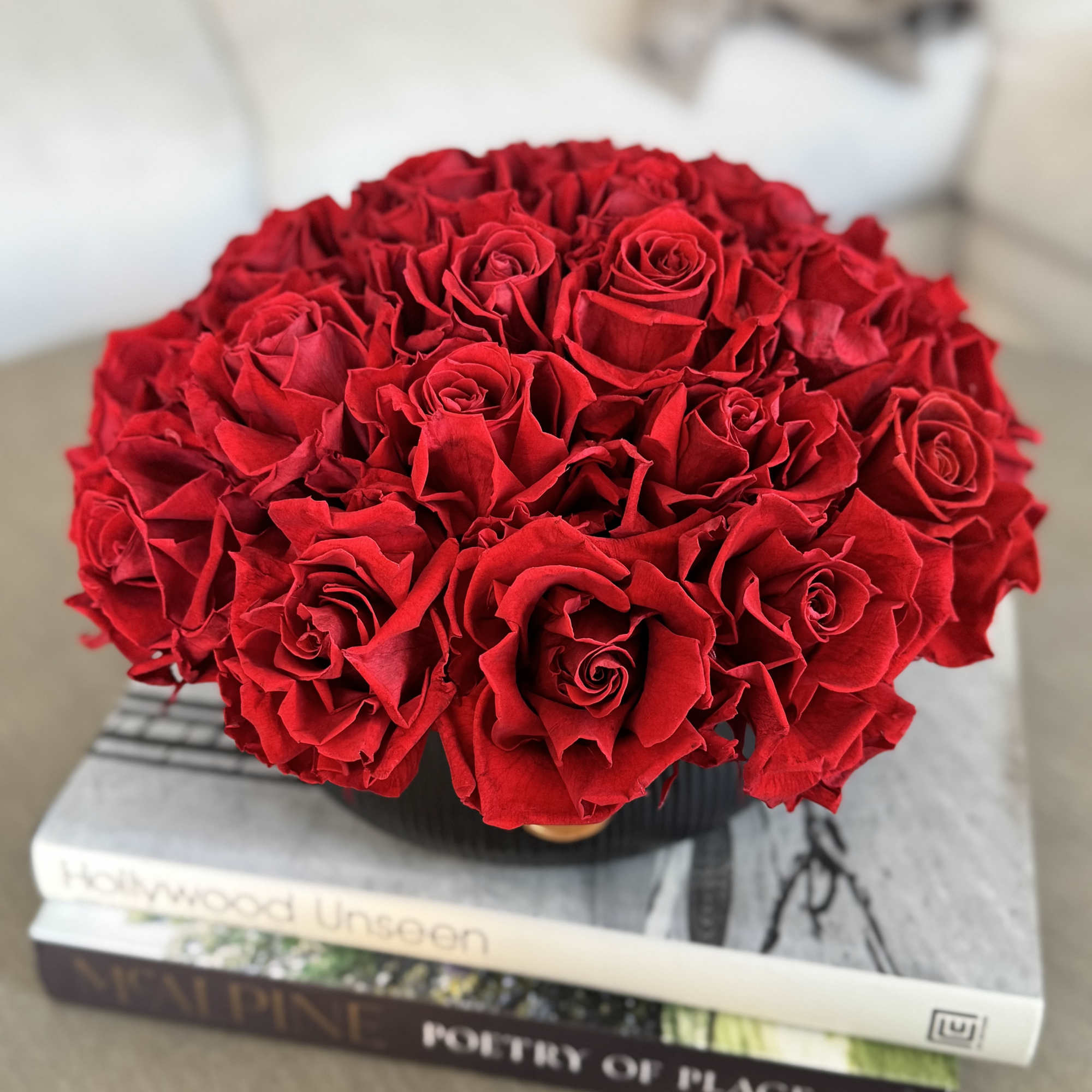 Round bouquet of red roses in a black container