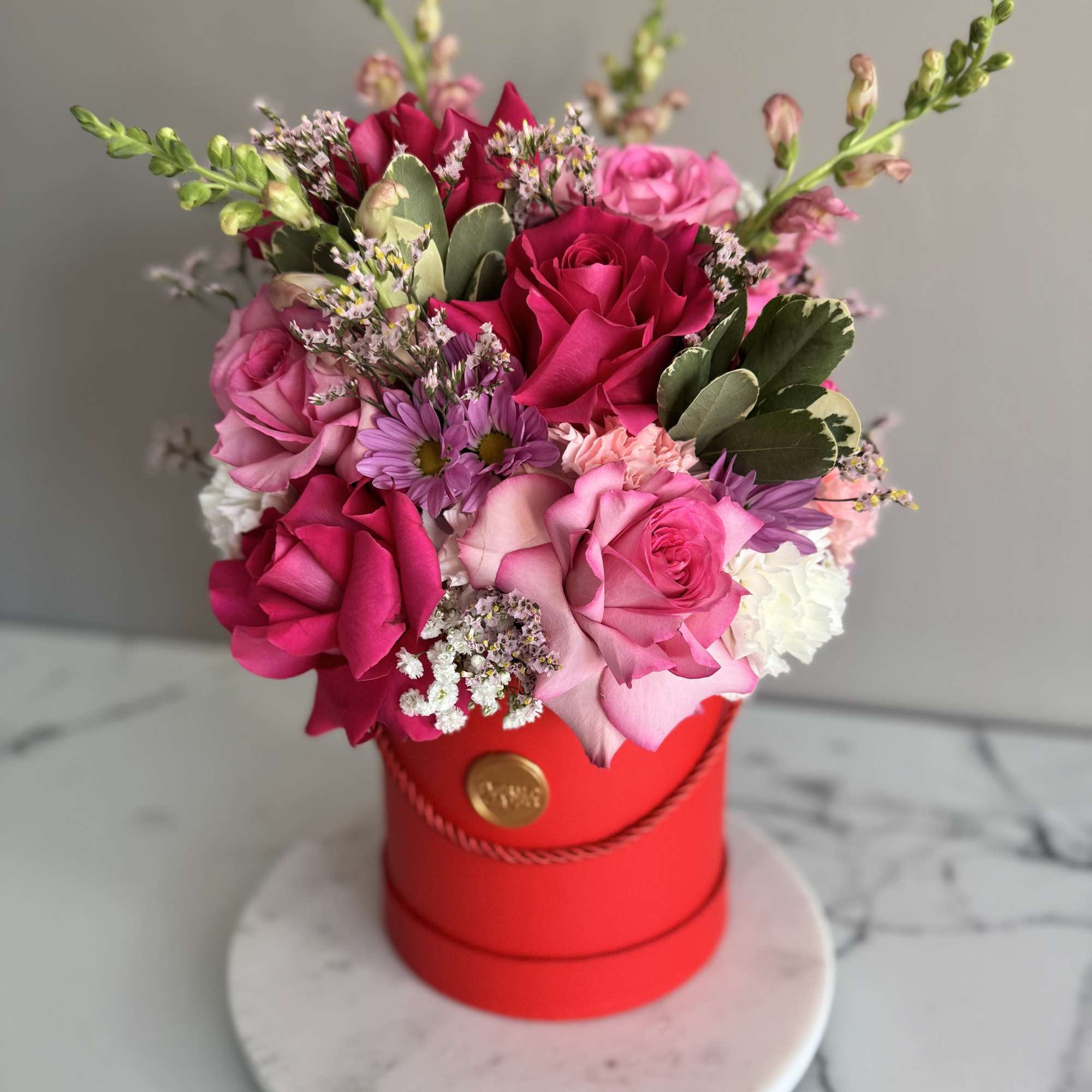 Pink and red rose bouquet in a red hat box