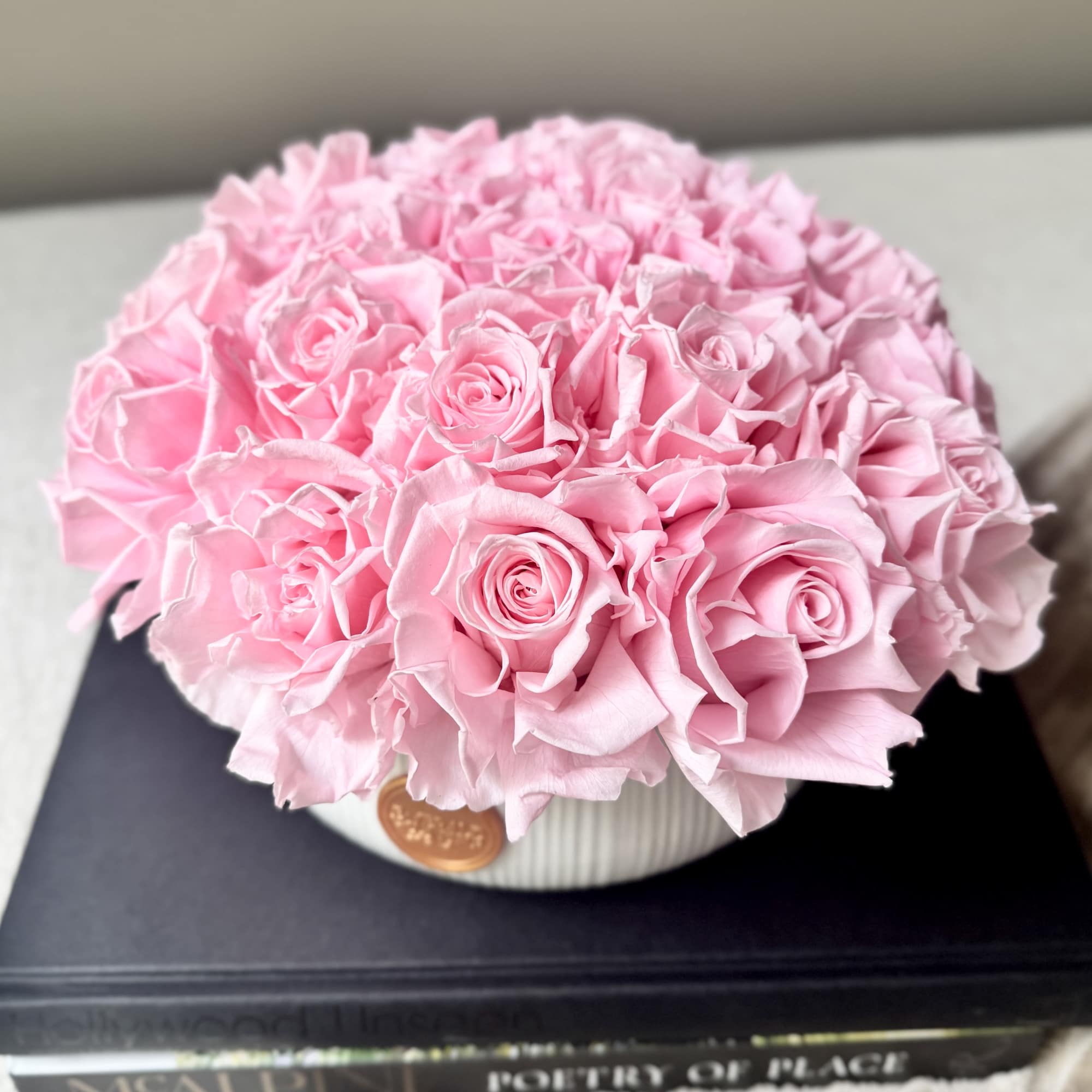 Round bouquet of pink roses in a white ribbed vase