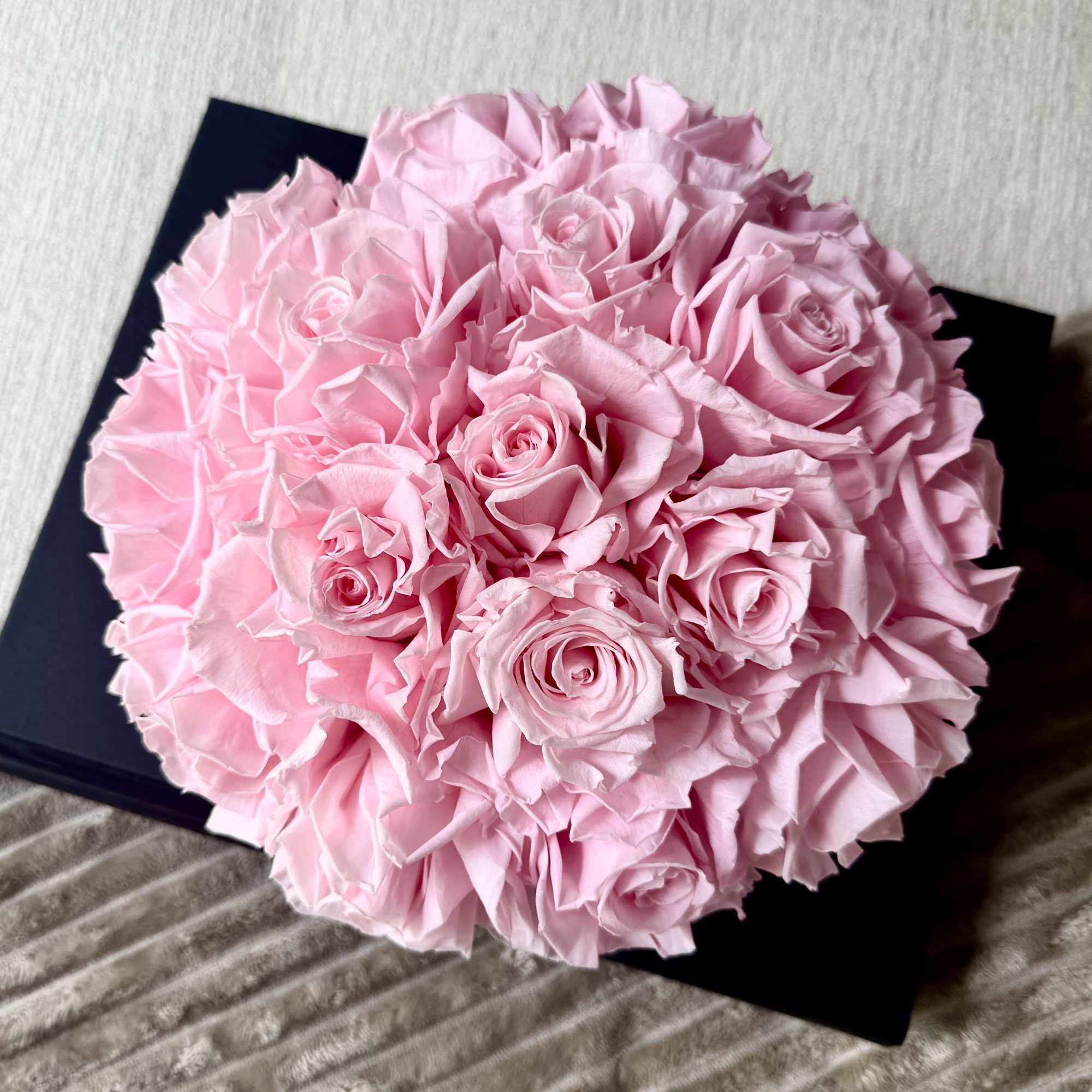 Round bouquet of pale pink roses in a black box
