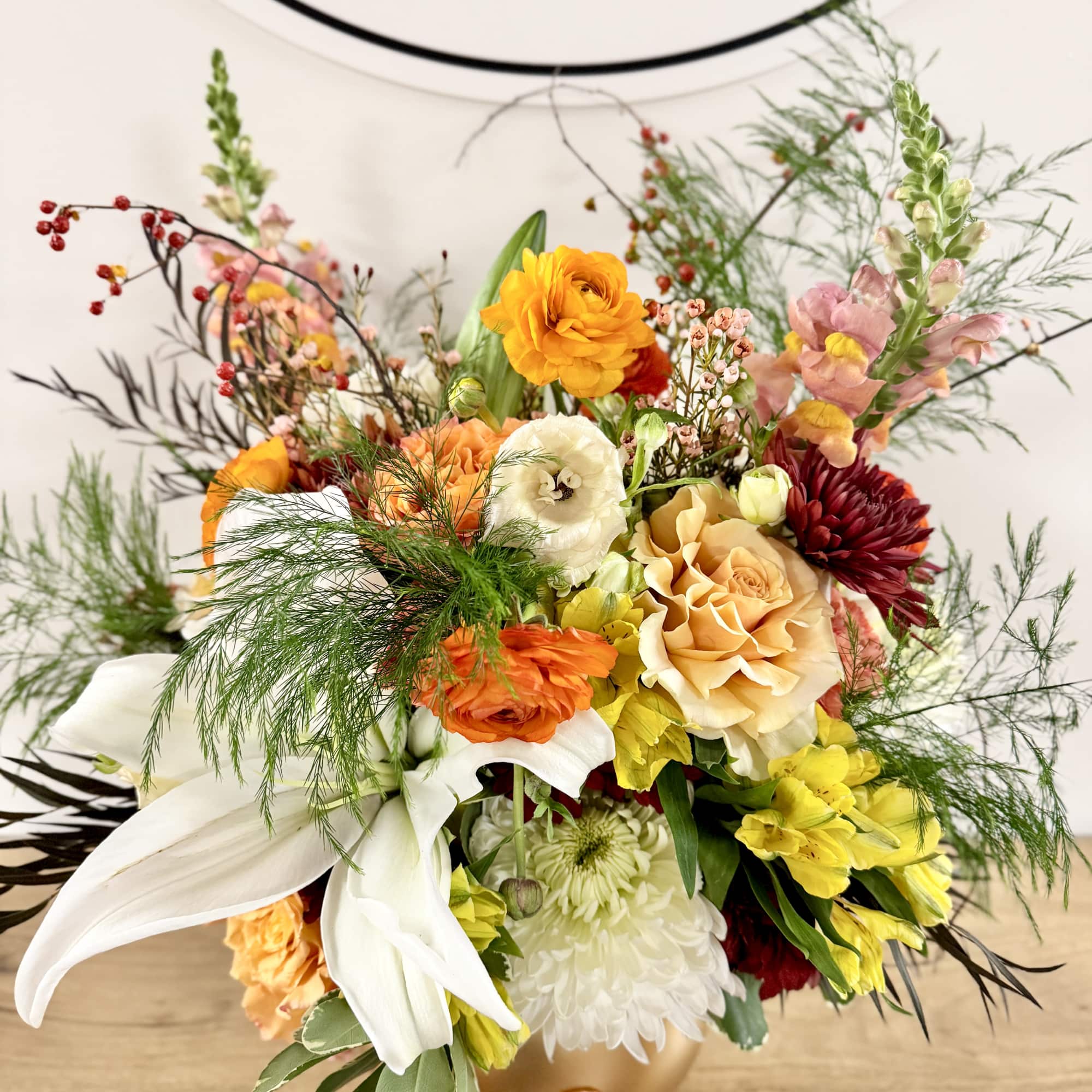 Mixed bouquet of orange, white, yellow, and red flowers in a gold vase