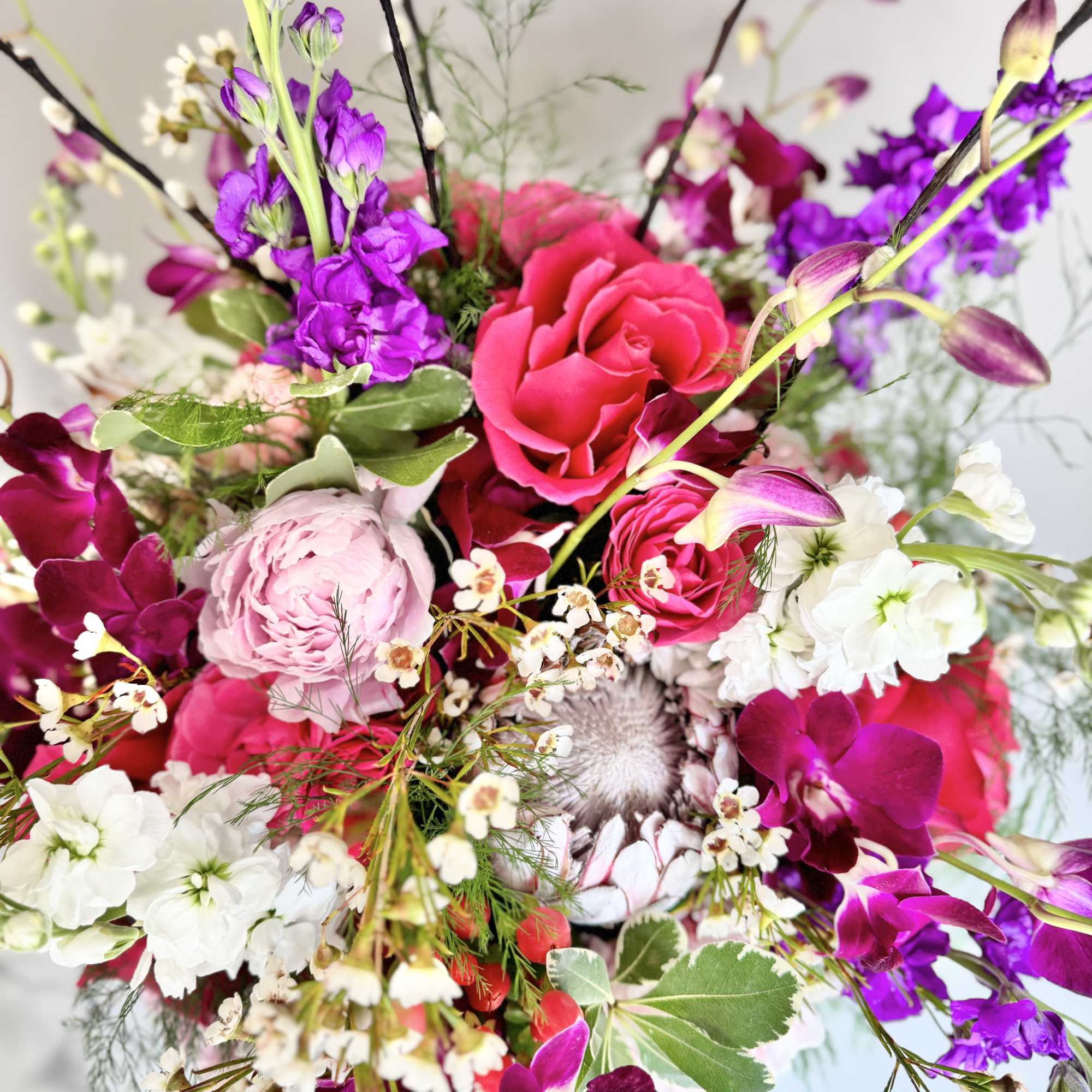 Bright mixed bouquet with pink roses, purple orchids, and white blooms