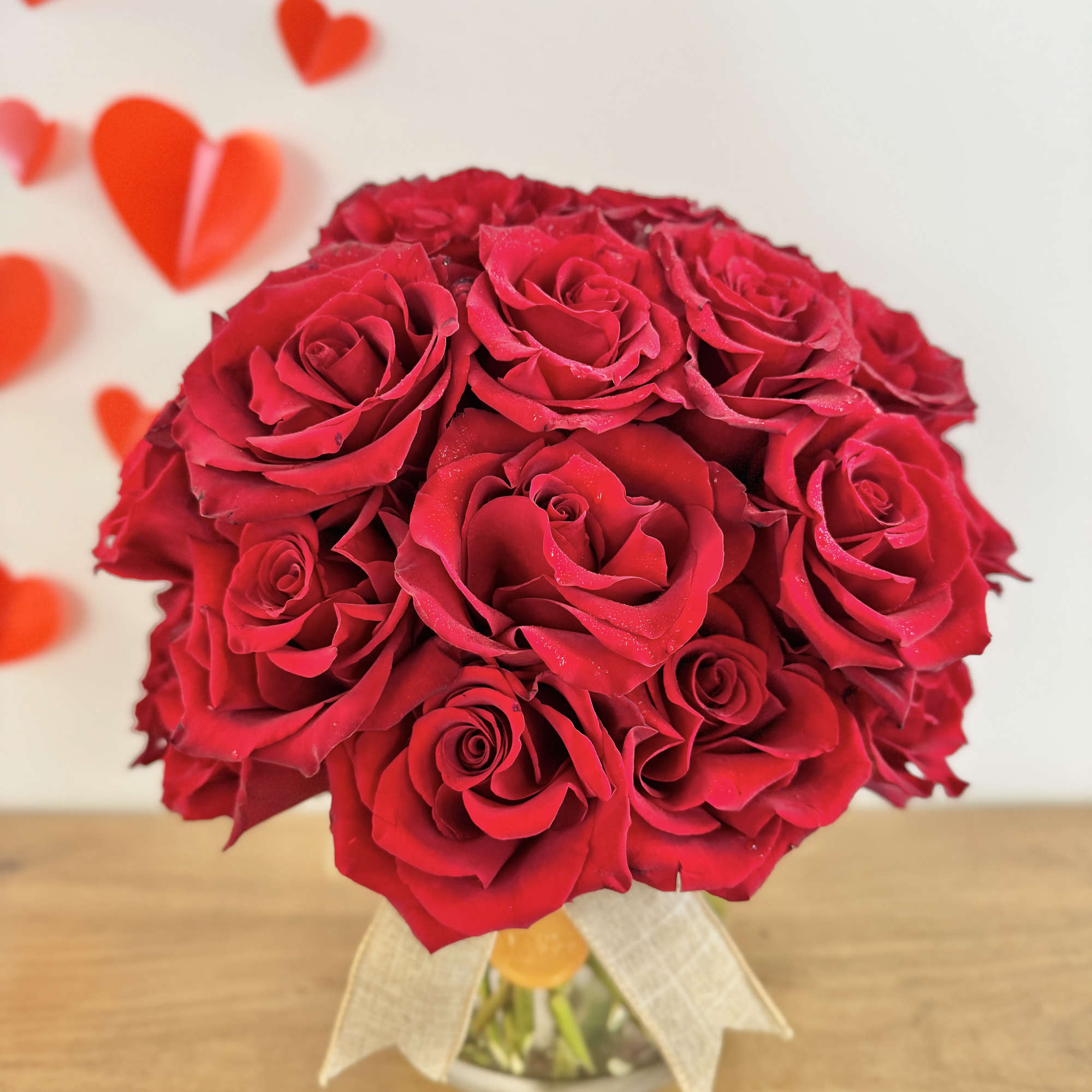 Red rose bouquet in a glass vase with a ribbon