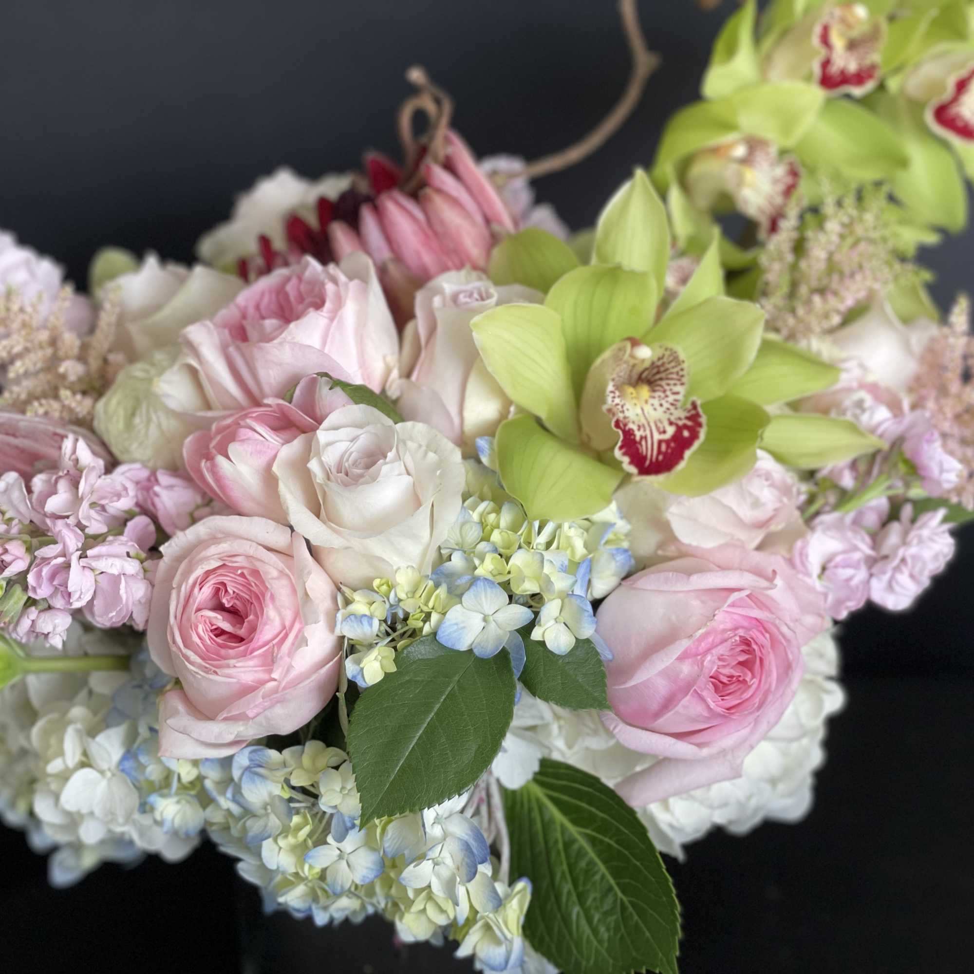 Bouquet of pink and white roses with green orchids and blue hydrangea
