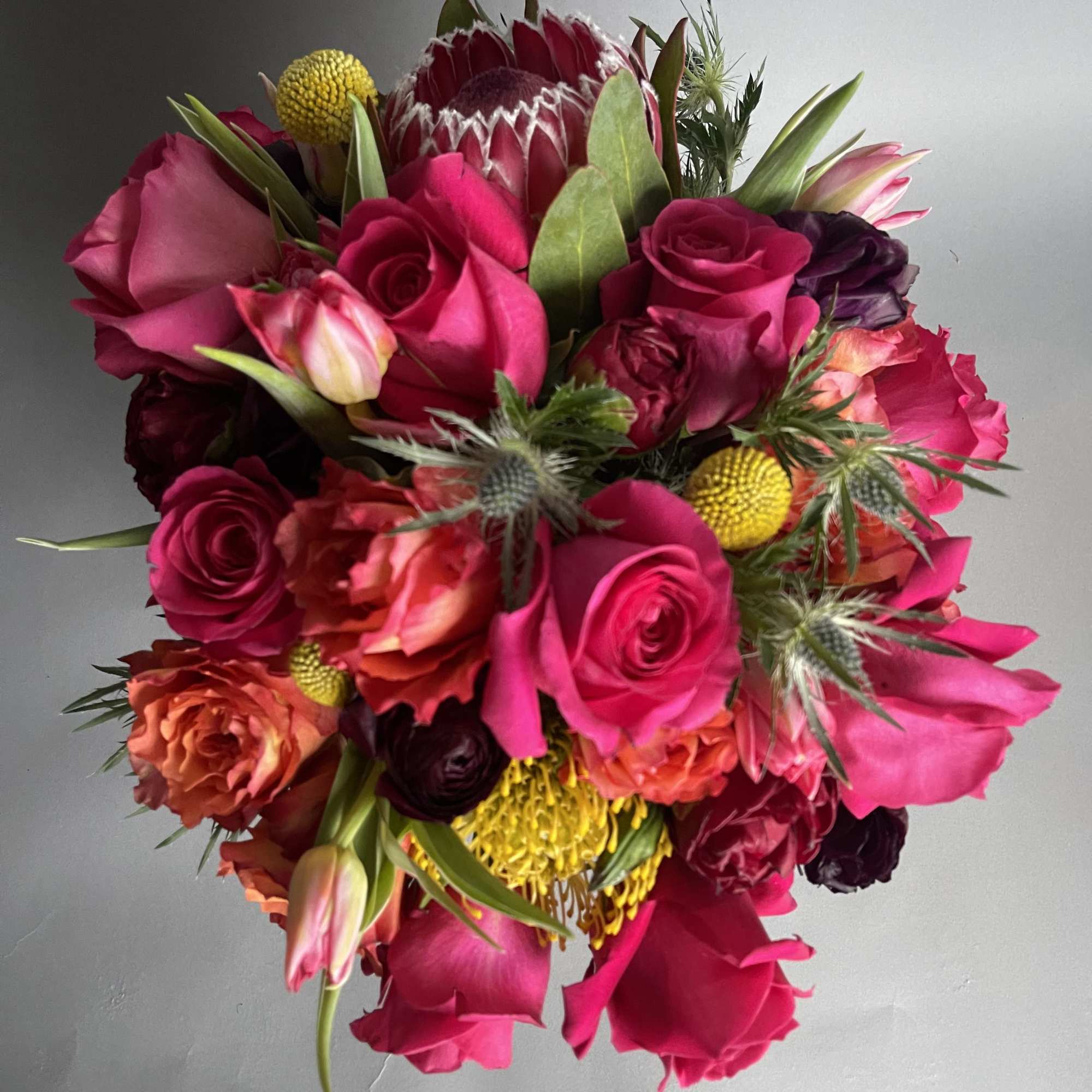 Bouquet of hot pink and coral roses with yellow accents