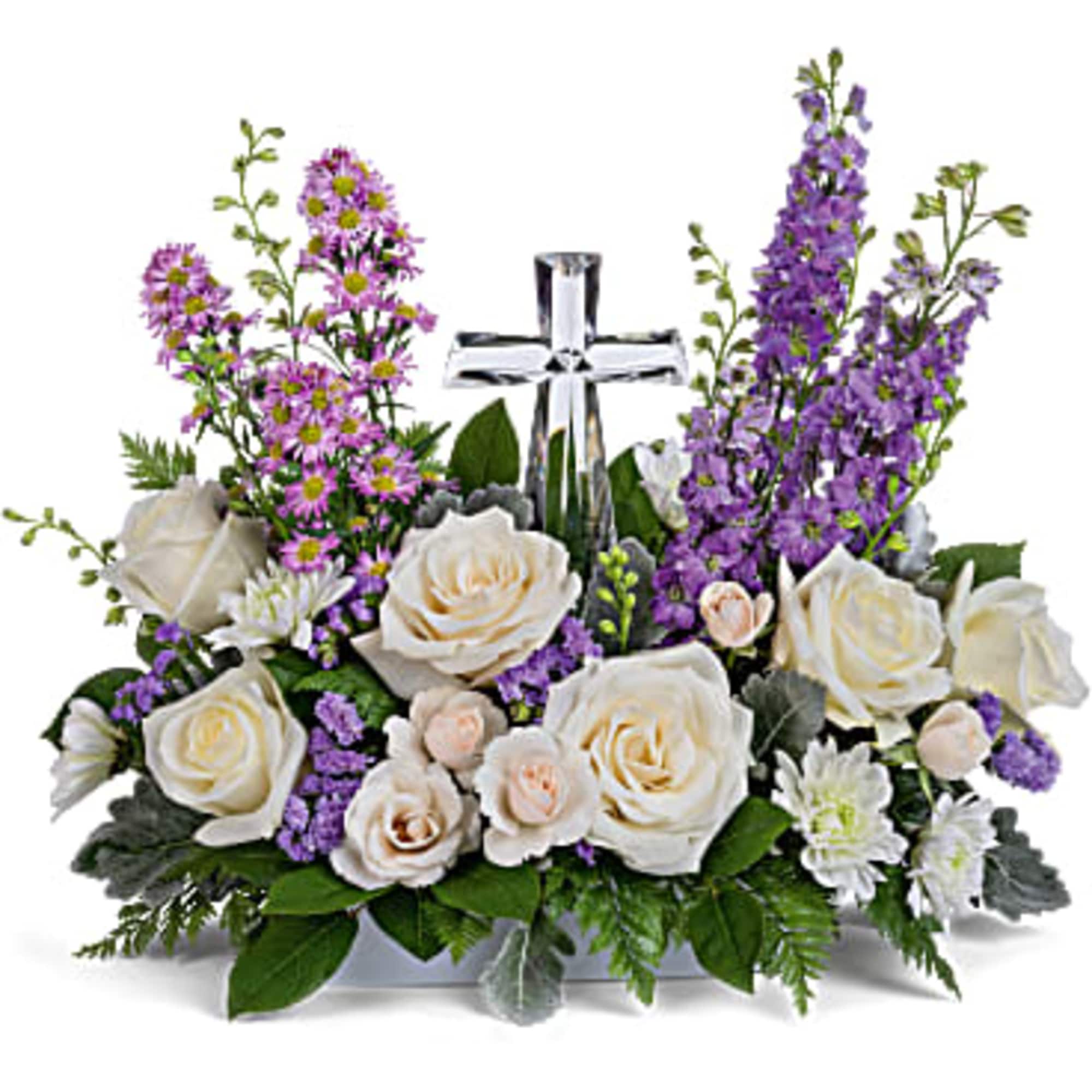 White roses and purple flowers arranged around a silver cross