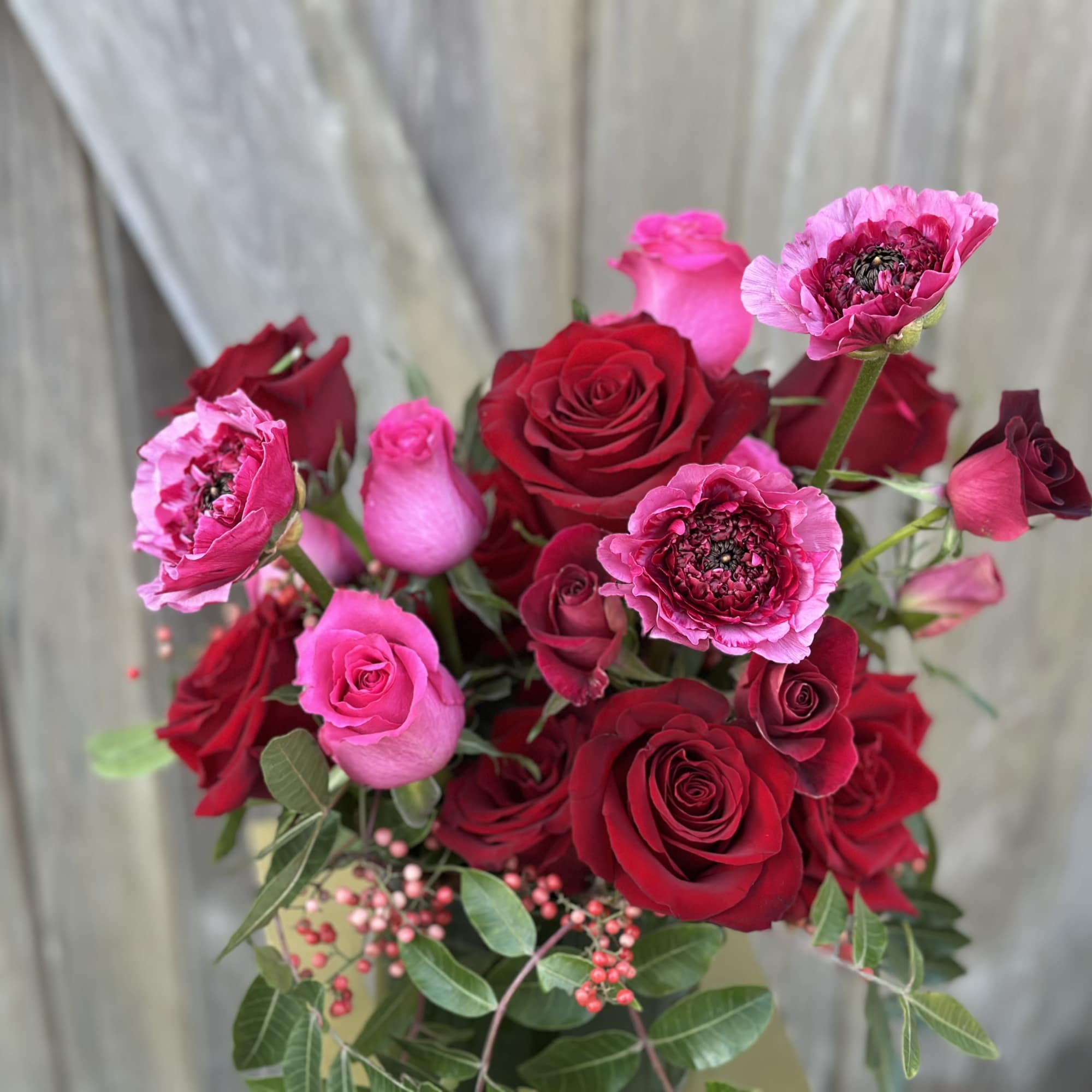 Bouquet of red and pink roses with pink ranunculus-like blooms