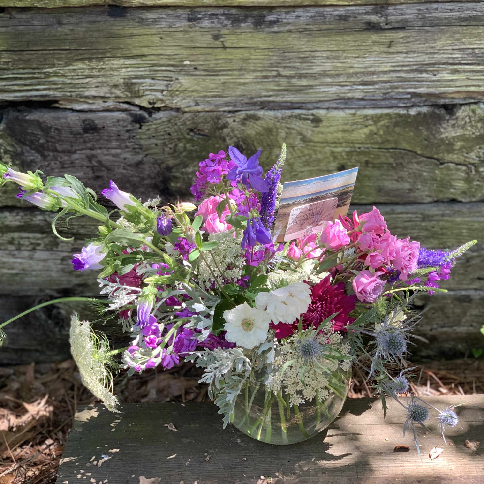Mixed bouquet of pink, purple, and white flowers in a clear glass vase