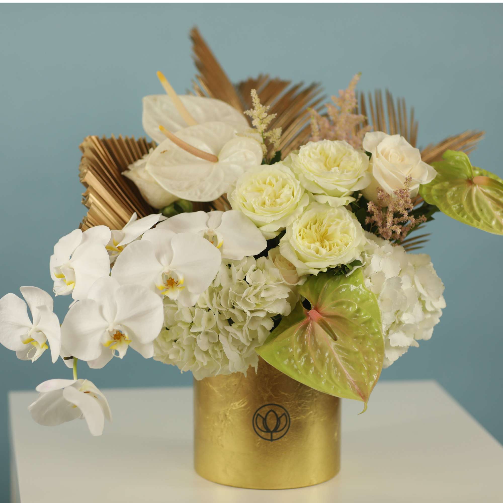 White orchids and pale roses in a gold vase