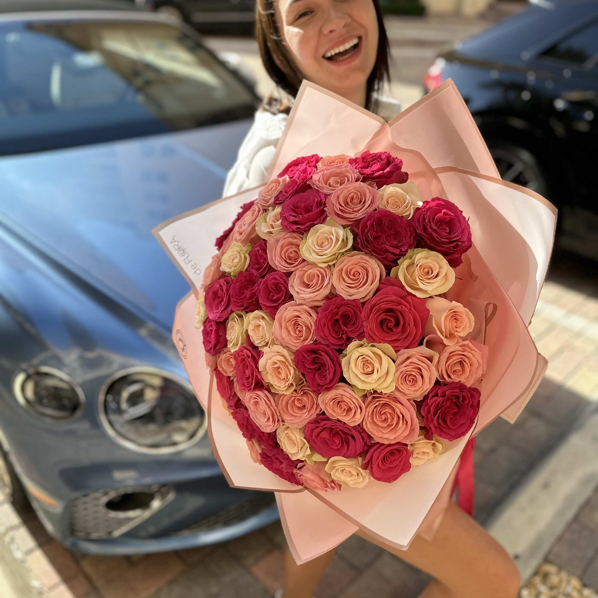 Woman holding a large bouquet of pink and peach roses