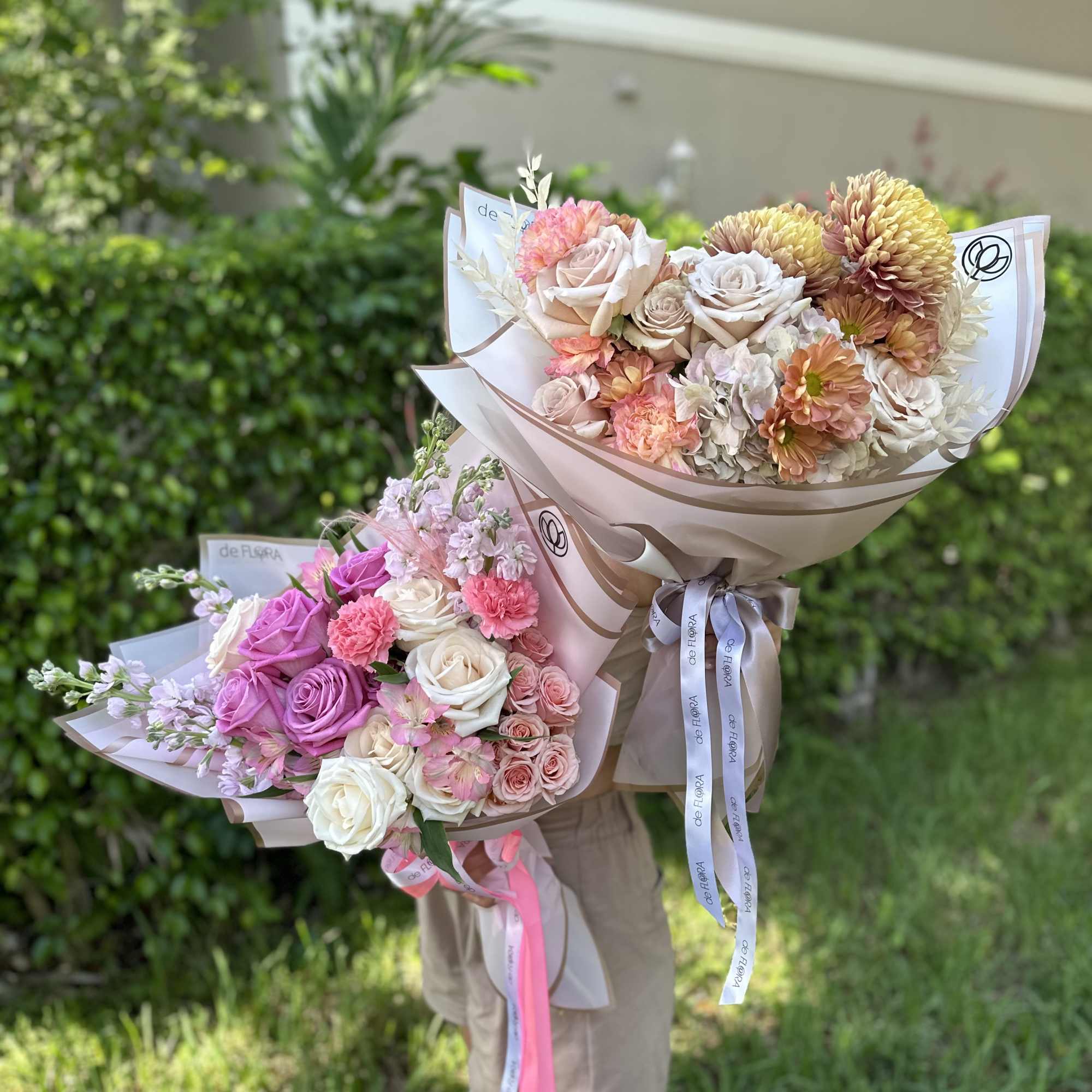 Two pastel bouquets of roses and mixed blooms wrapped in paper