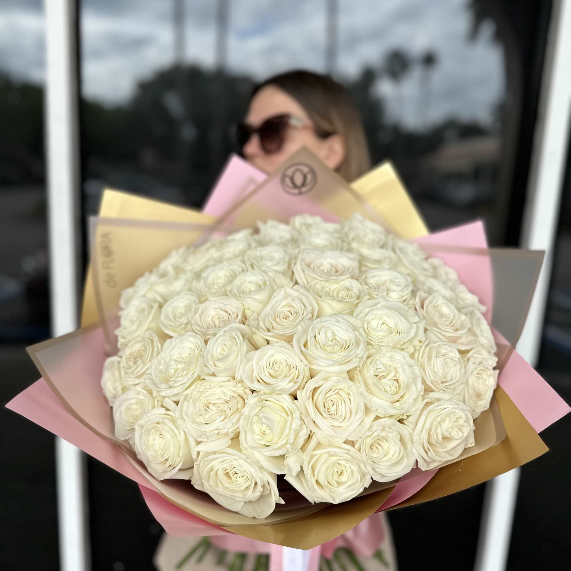 Large bouquet of cream roses wrapped in pink and gold paper