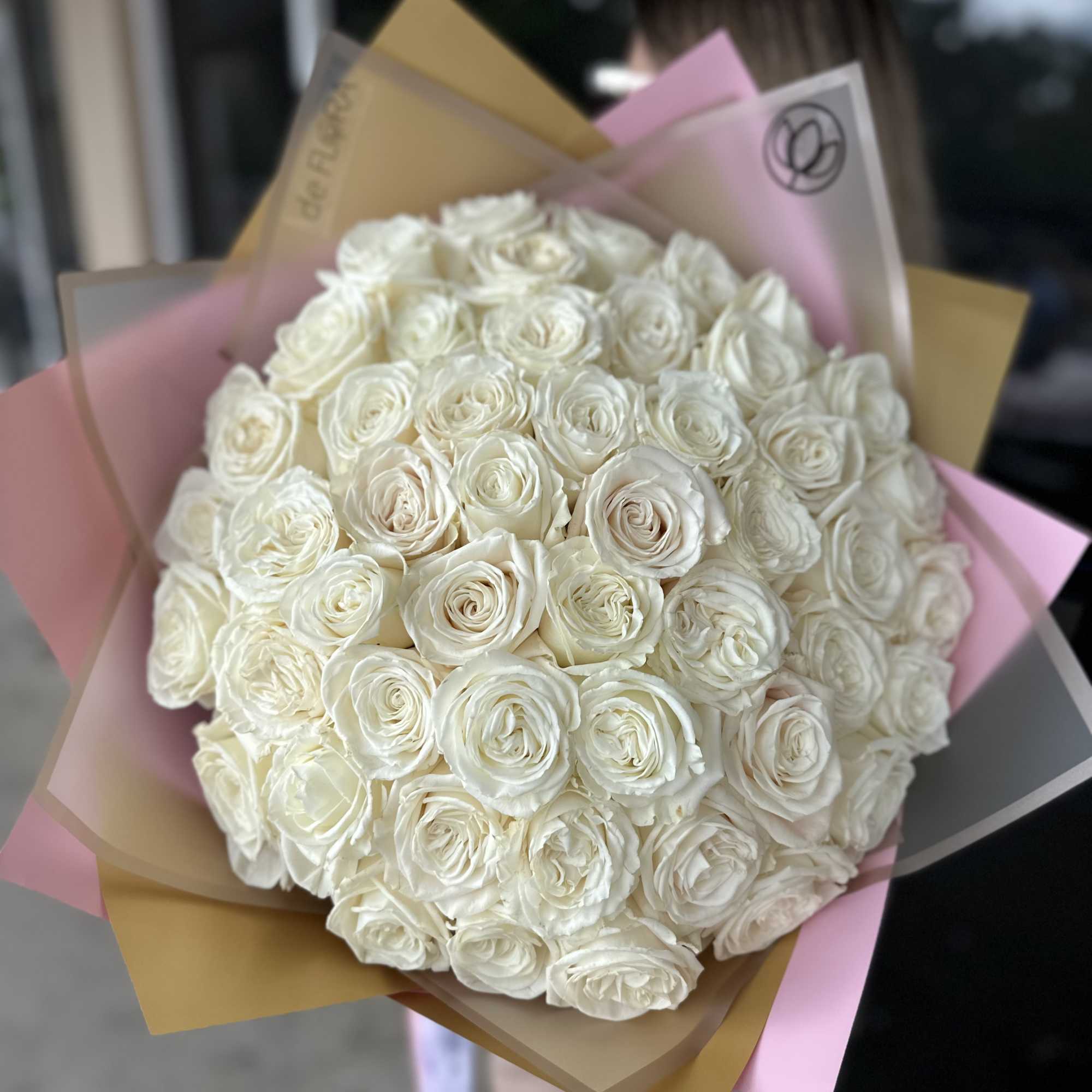 Large bouquet of white roses wrapped in pink and tan paper